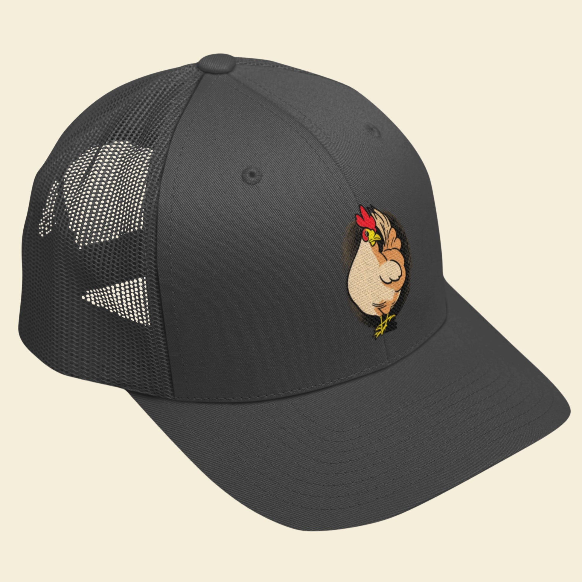 Black trucker cap with a cartoon chicken design on a beige background.