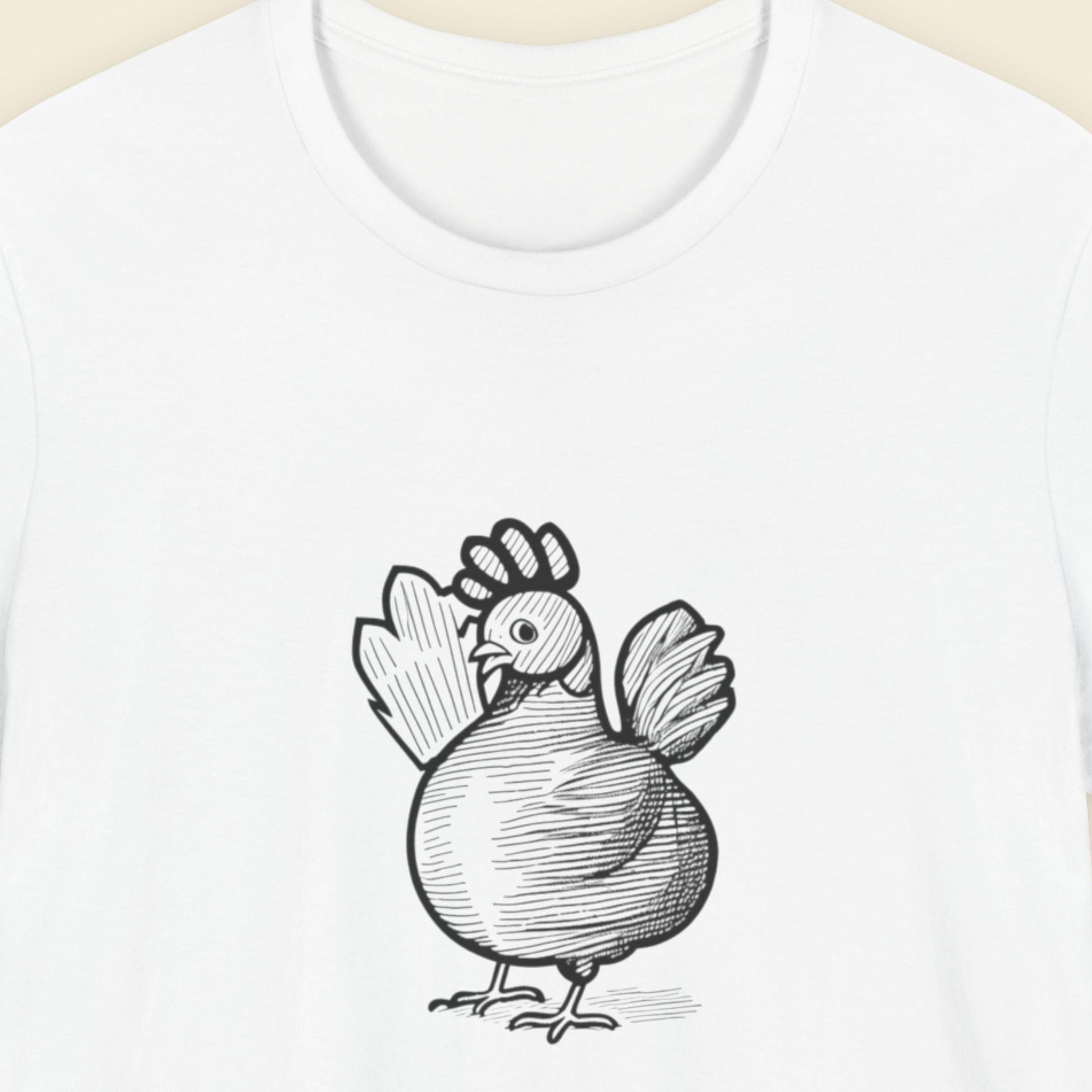 white shirt with a pen and ink drawing of a cartoon chicken on a beige background.