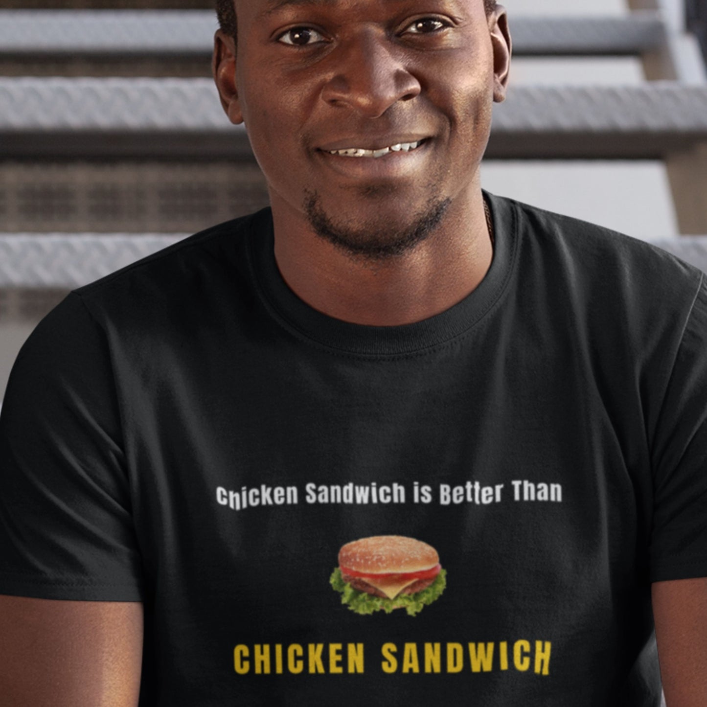 Man wearing a black t-shirt with a humorous chicken sandwich graphic and text.