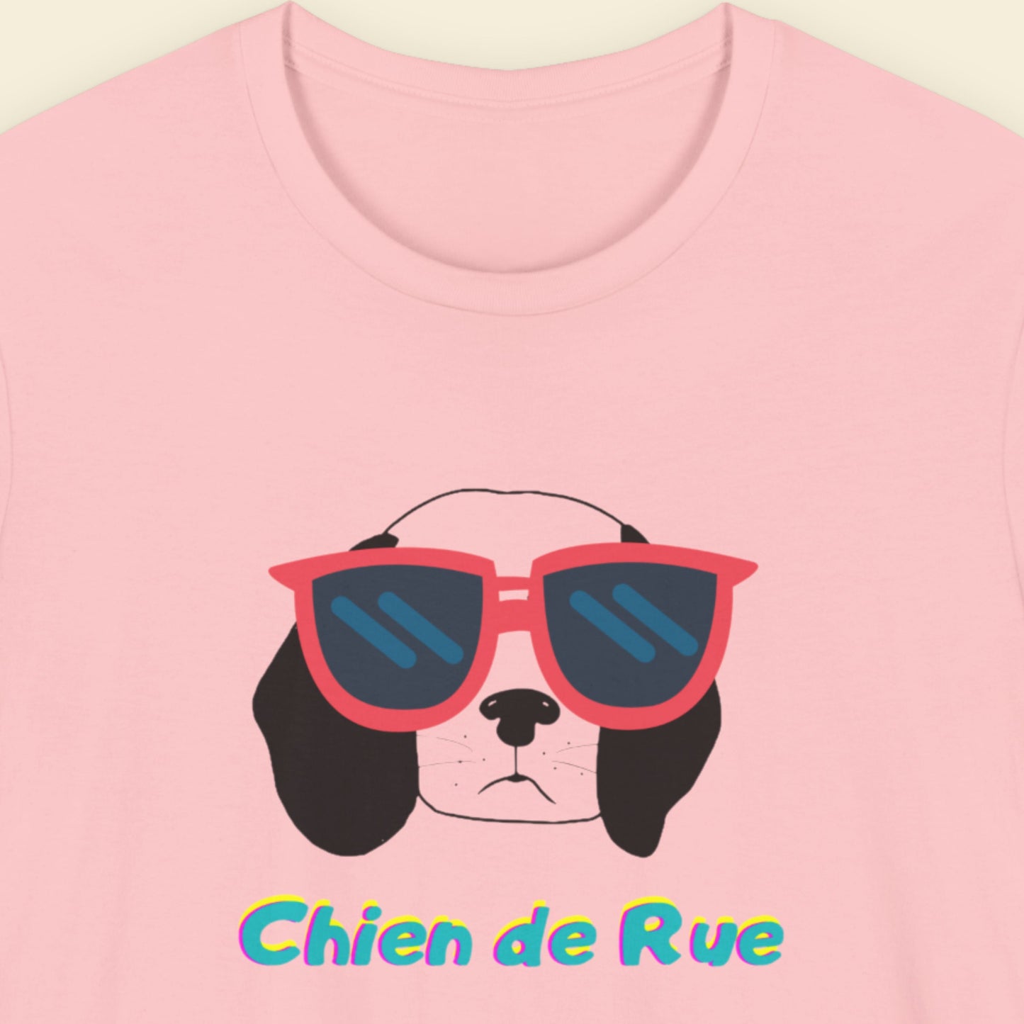 Pink t-shirt with a dog wearing sunglasses and 'Chien de Rue' text on a light pink background.