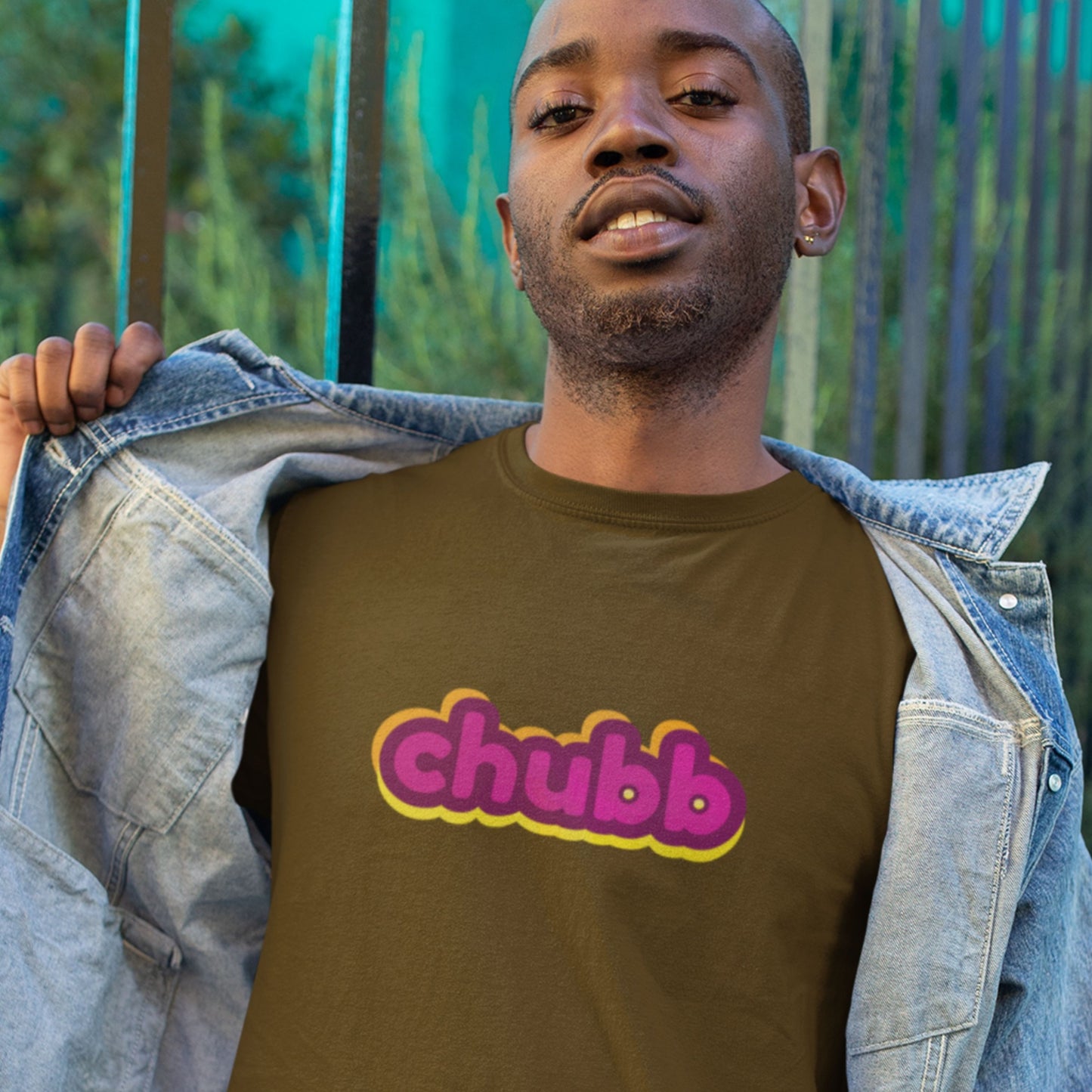 Man wearing a brown t-shirt with multicolored 'chubb' text outside.