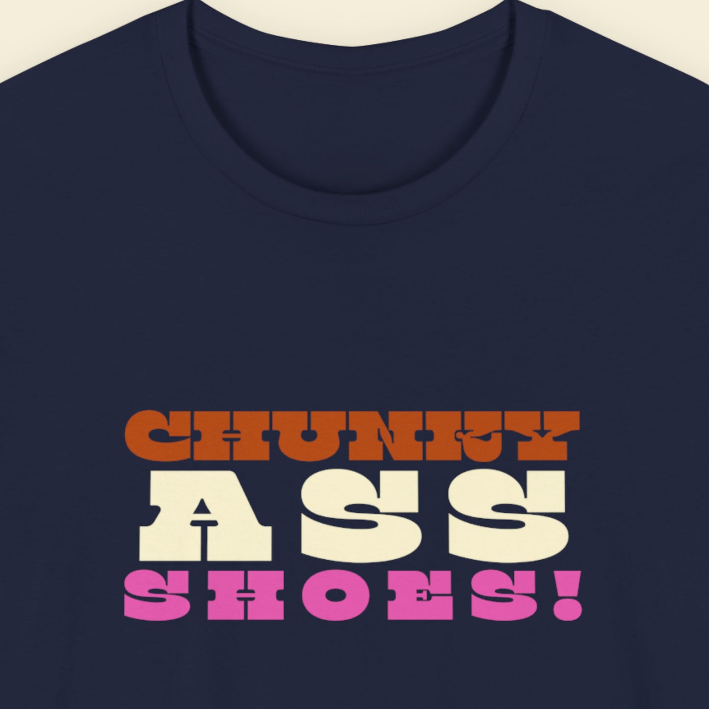 Navy blue t-shirt with colorful text design on a beige background.