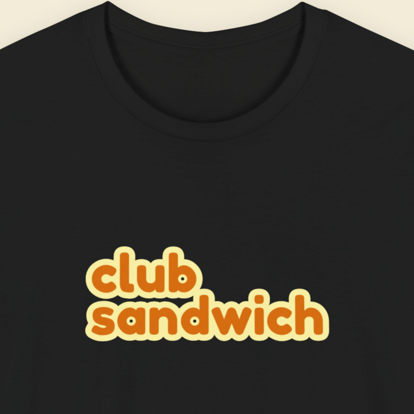 Black t-shirt with multicolored 'club sandwich' text on a beige background.