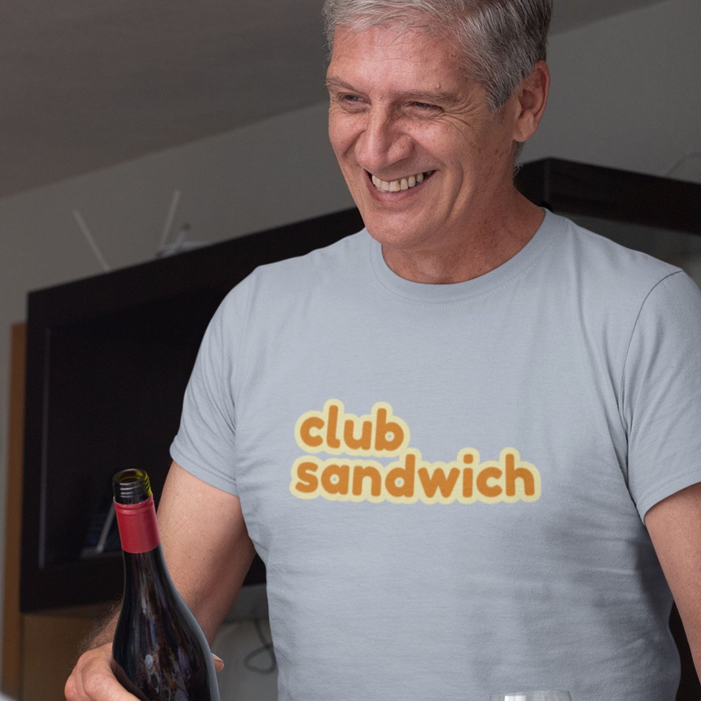 Man wearing a 'club sandwich' t-shirt holding a bottle of wine.