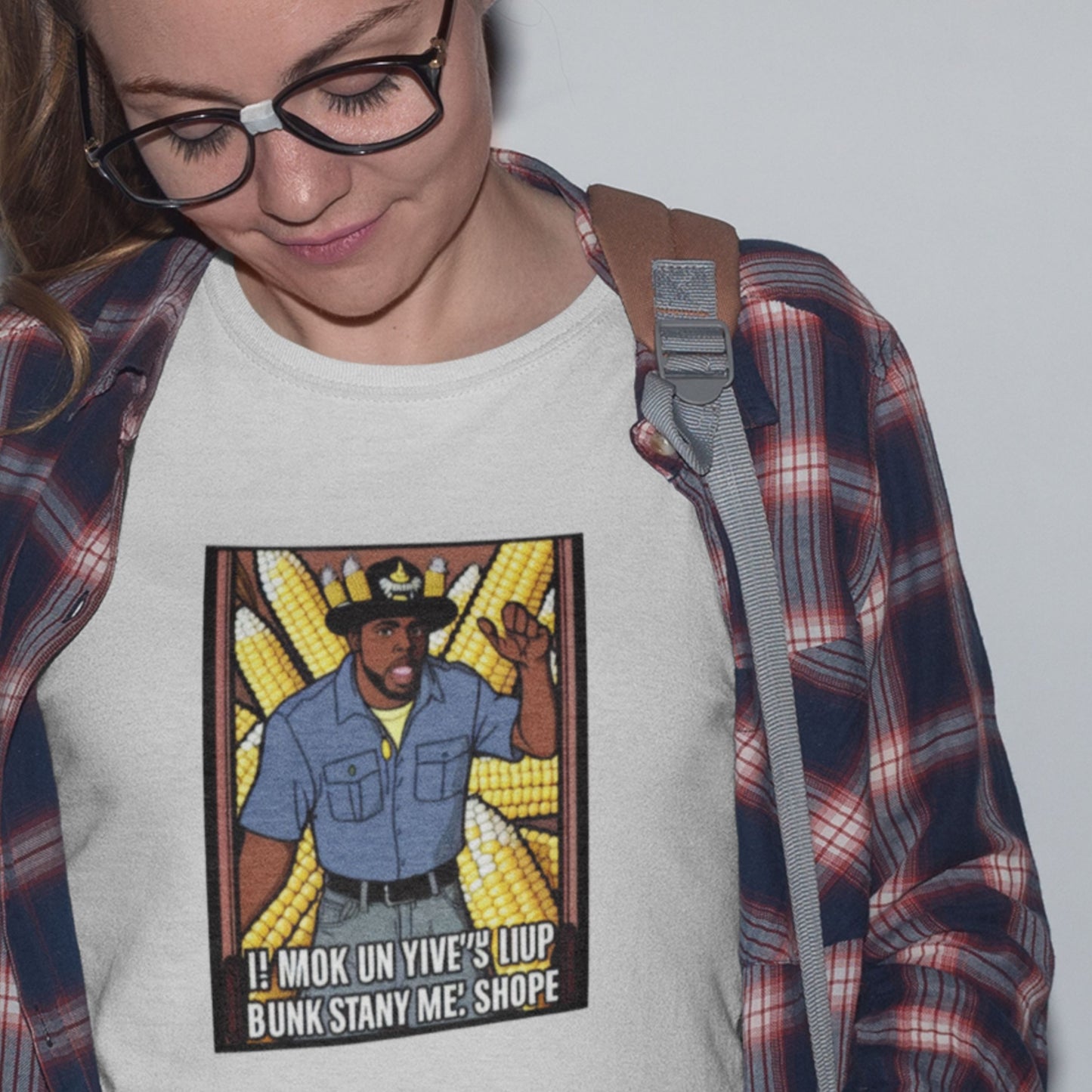 Person wearing a white t-shirt with a graphic design of a person in a blue shirt and cowboy hat, surrounded by corn stalks.