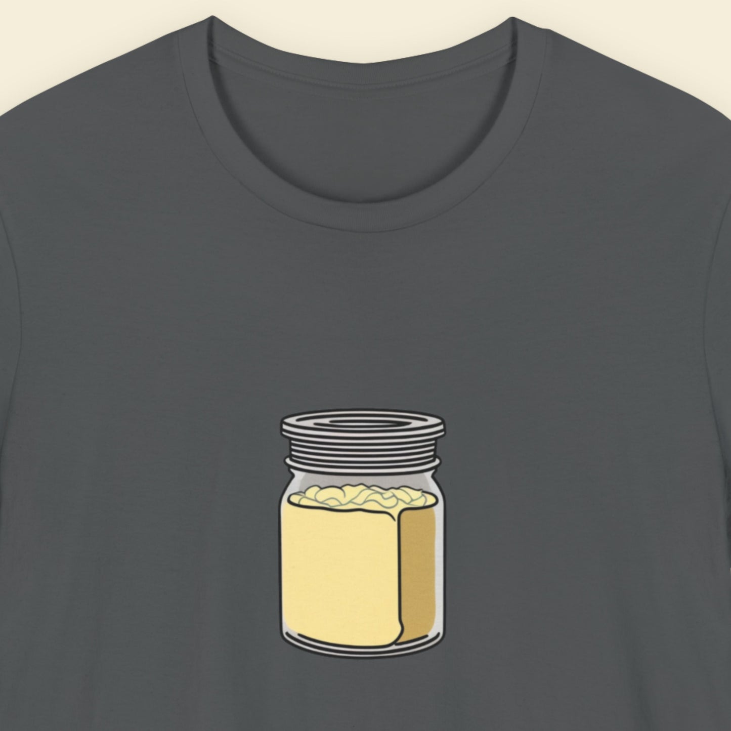 Grey shirt with a drawing of a square shaped jar of creamy mayo on a beige background.