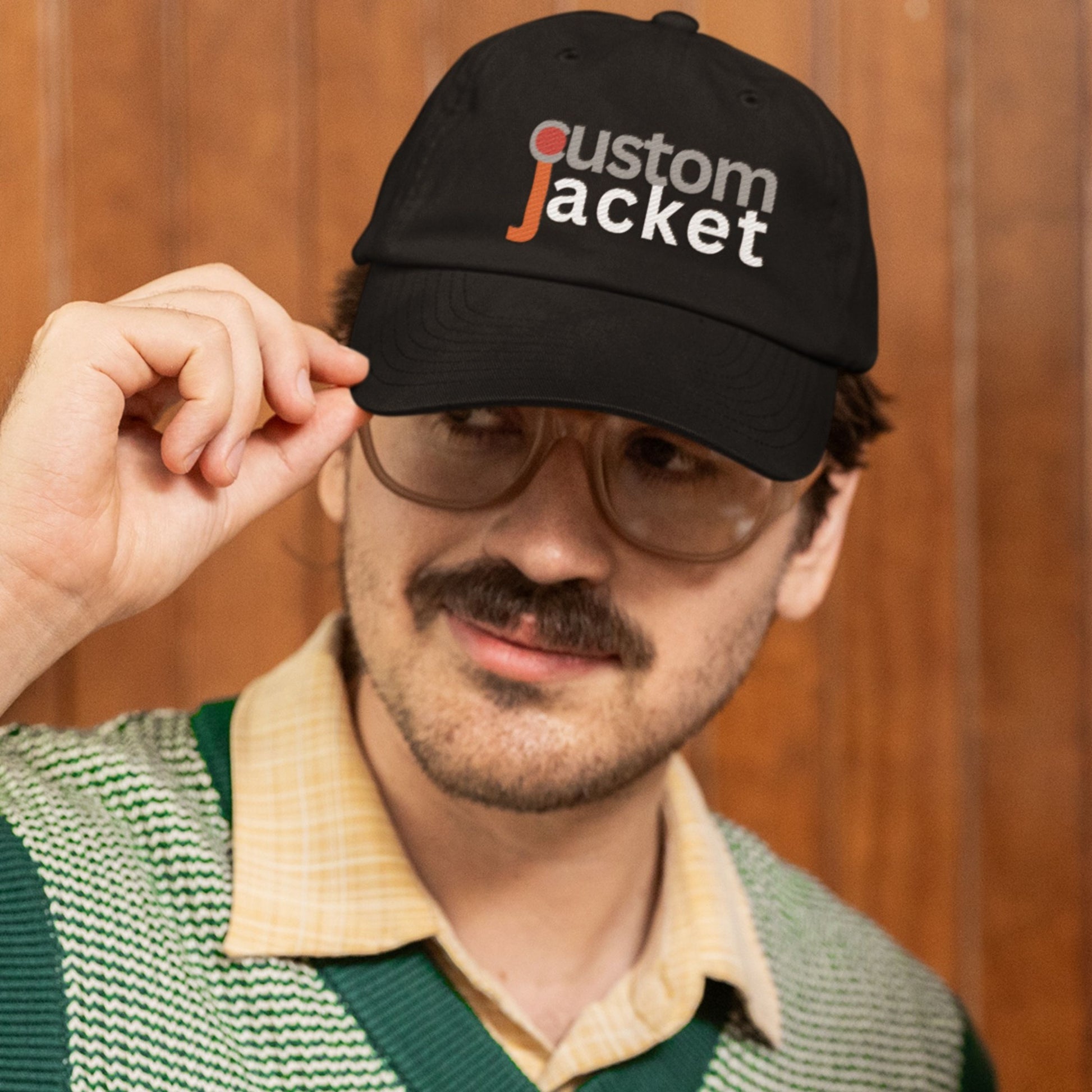Man wearing a black cap with 'custom jacket' text against a wooden background.