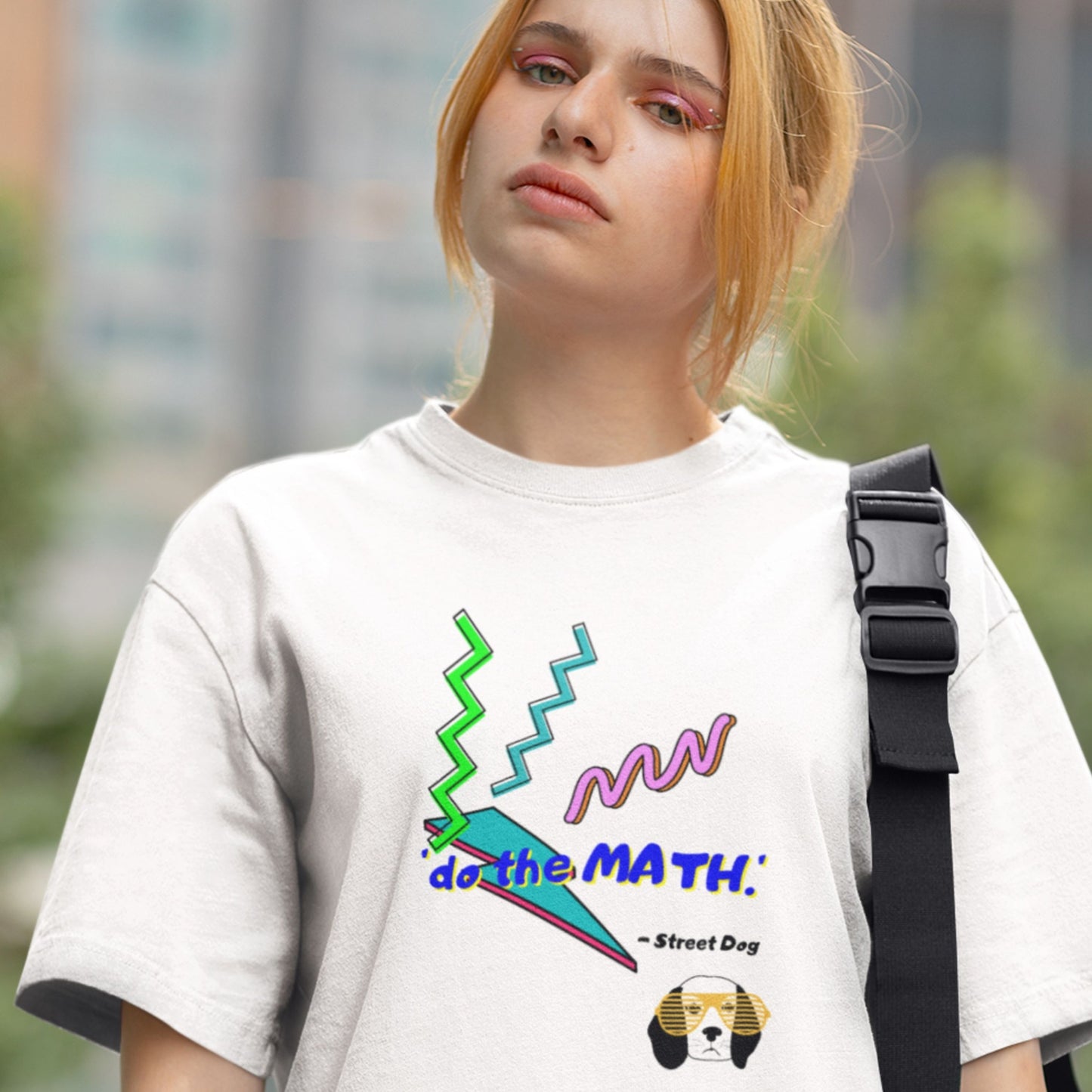 Person wearing a white t-shirt with colorful graphics and text, standing outdoors.