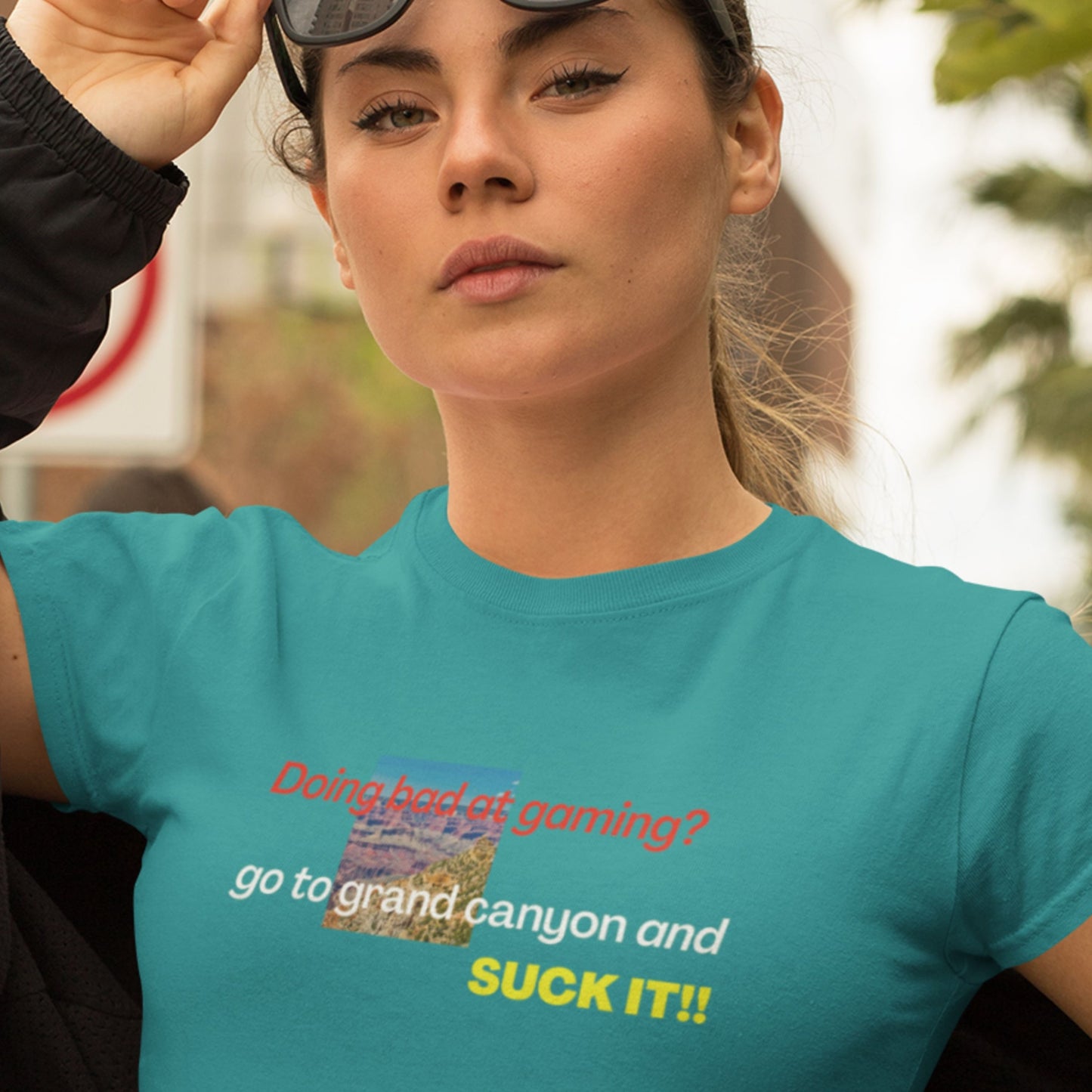 Woman wearing a teal t-shirt with humorous text and graphic, outdoors.