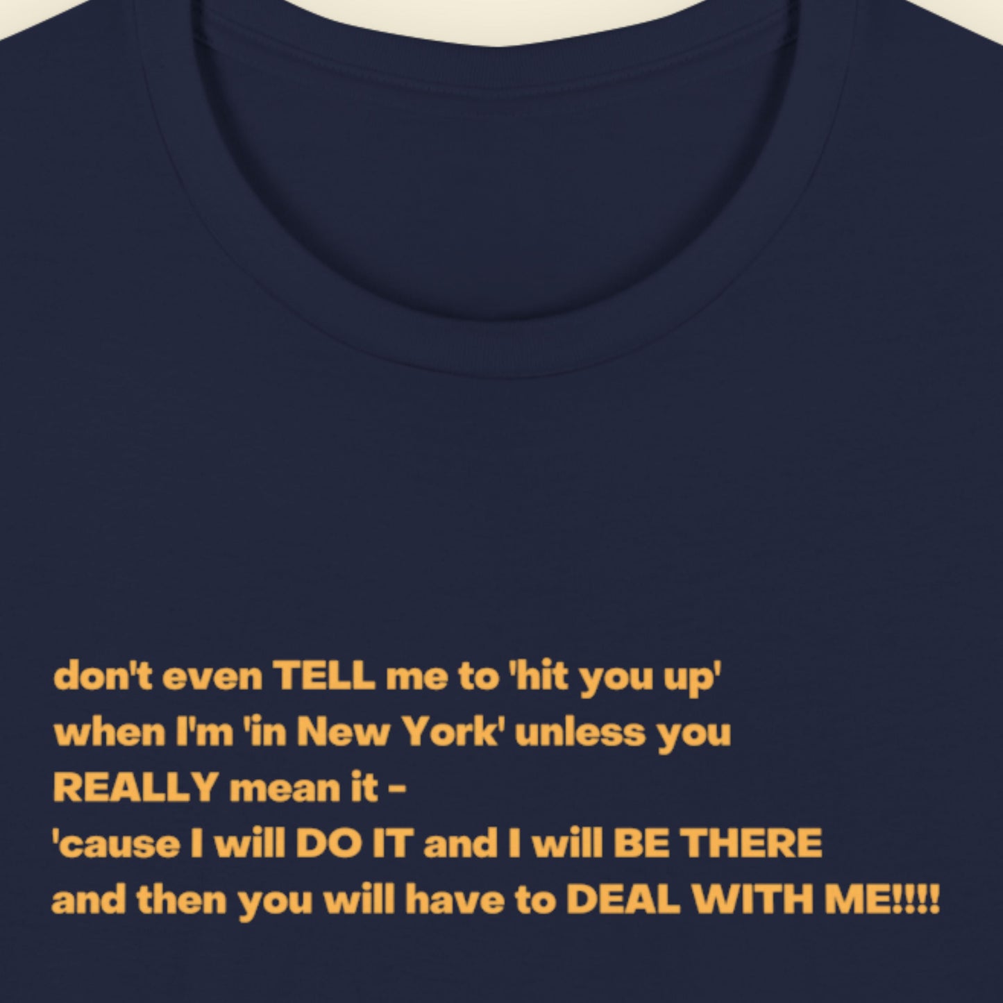 Navy blue t-shirt with humorous colorful text on a beige background.