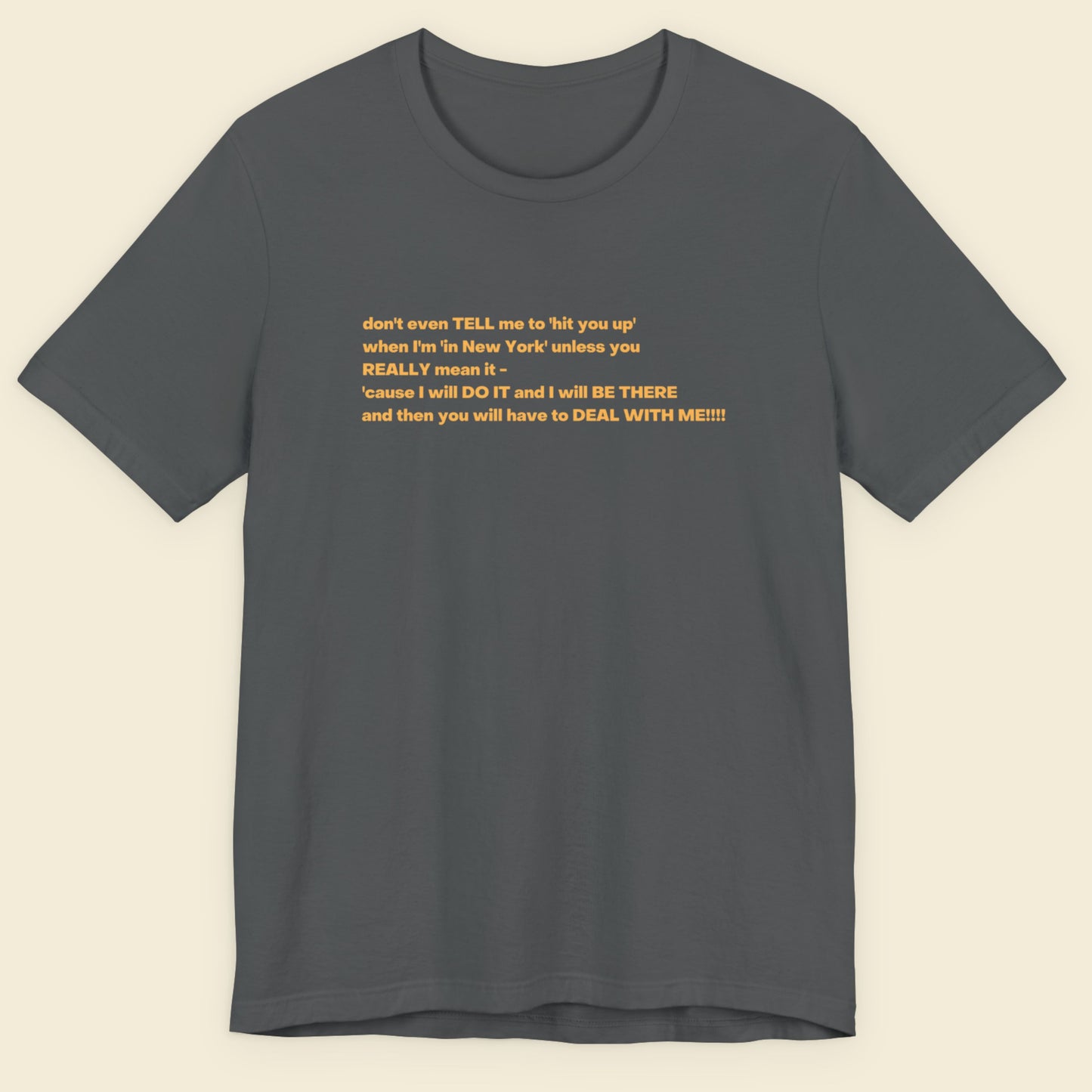 Grey t-shirt with humorous colorful text on a beige background.