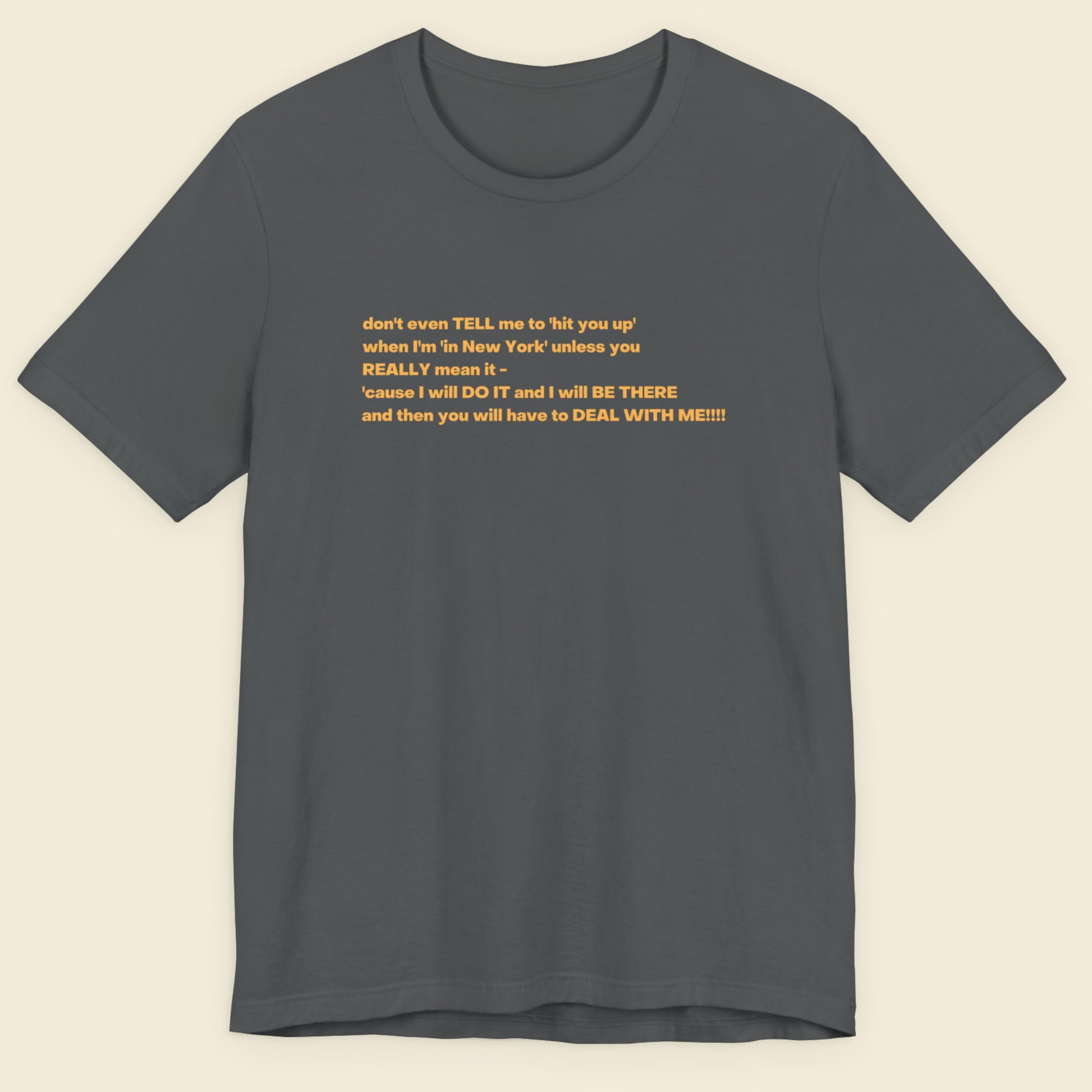 Grey t-shirt with humorous colorful text on a beige background.