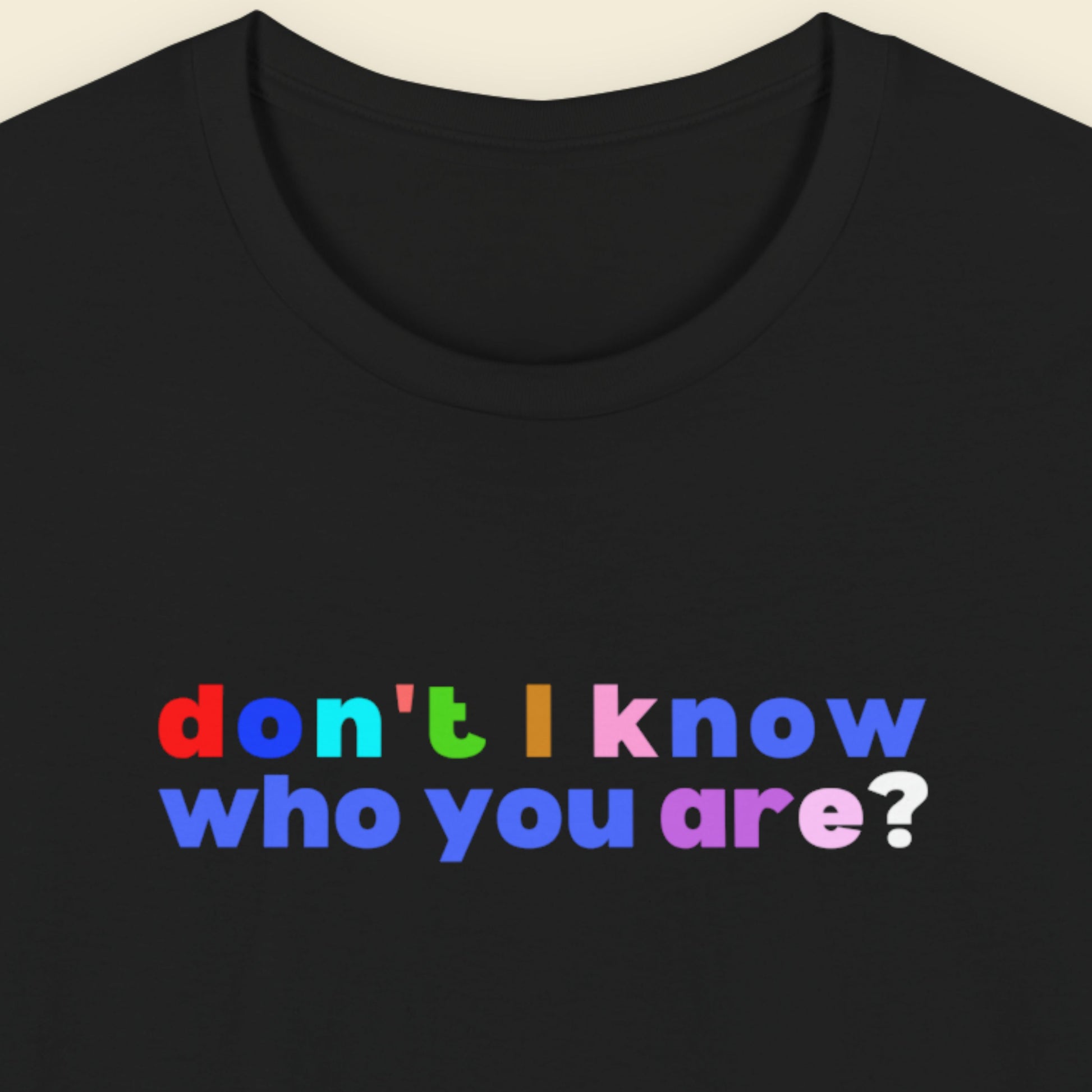 Black t-shirt with colorful text 'don't I know who you are?' on a beige background.