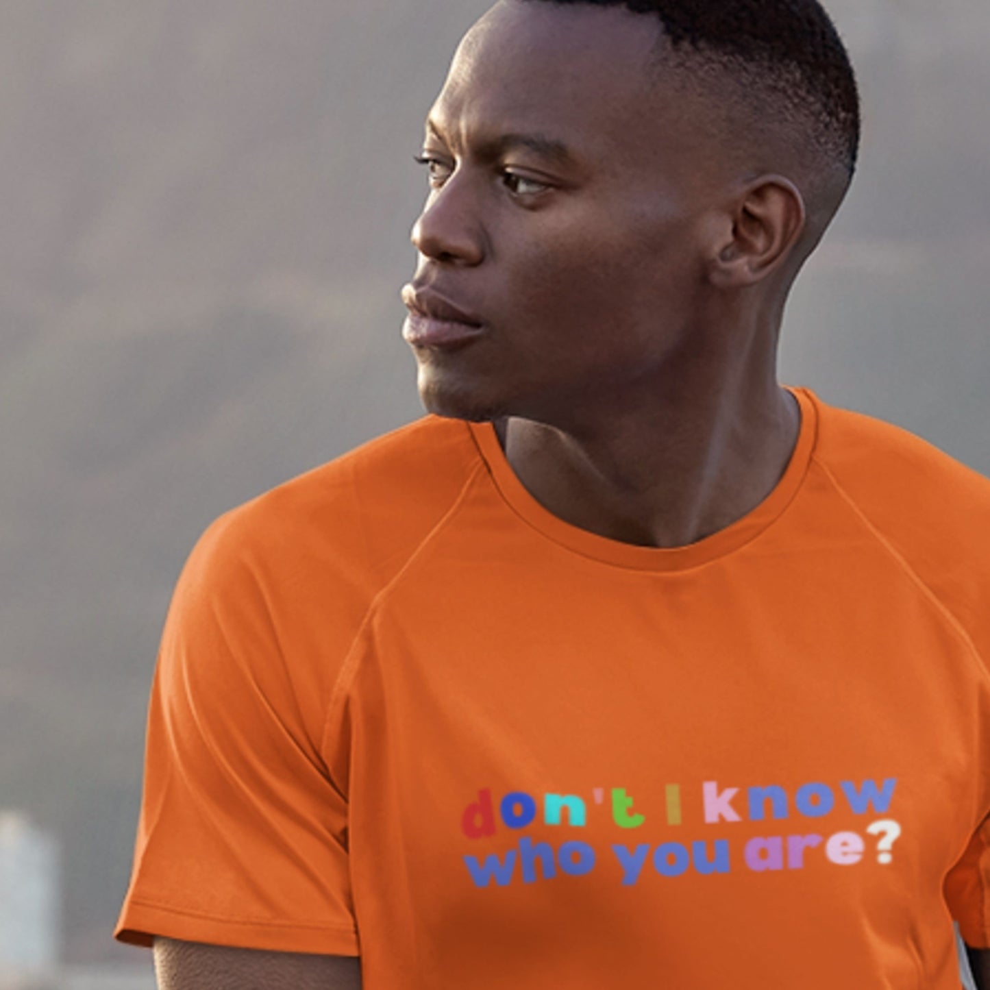 Man wearing an orange t-shirt with a colorful text design.