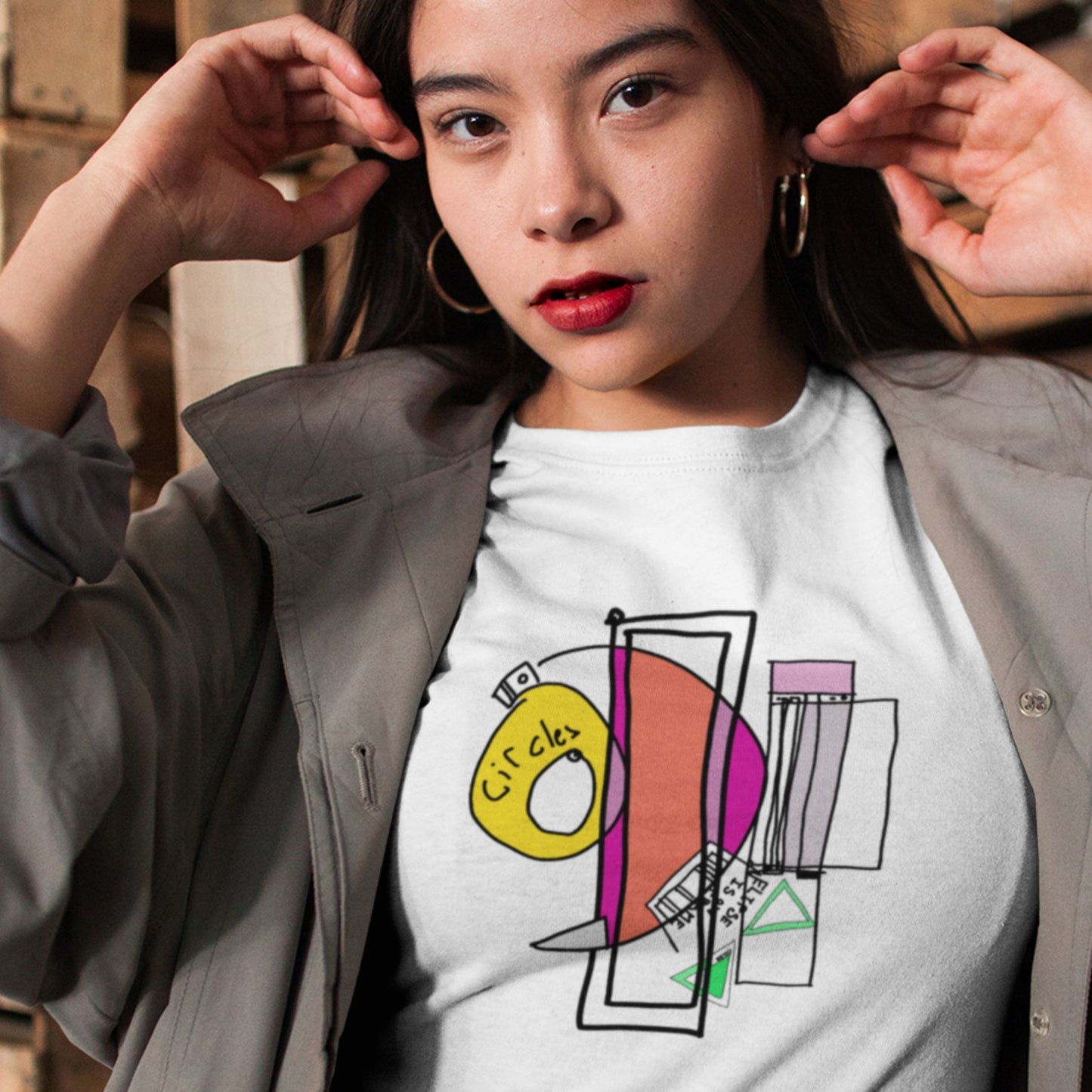Woman wearing a white t-shirt with a colorful abstract drawing indoors.