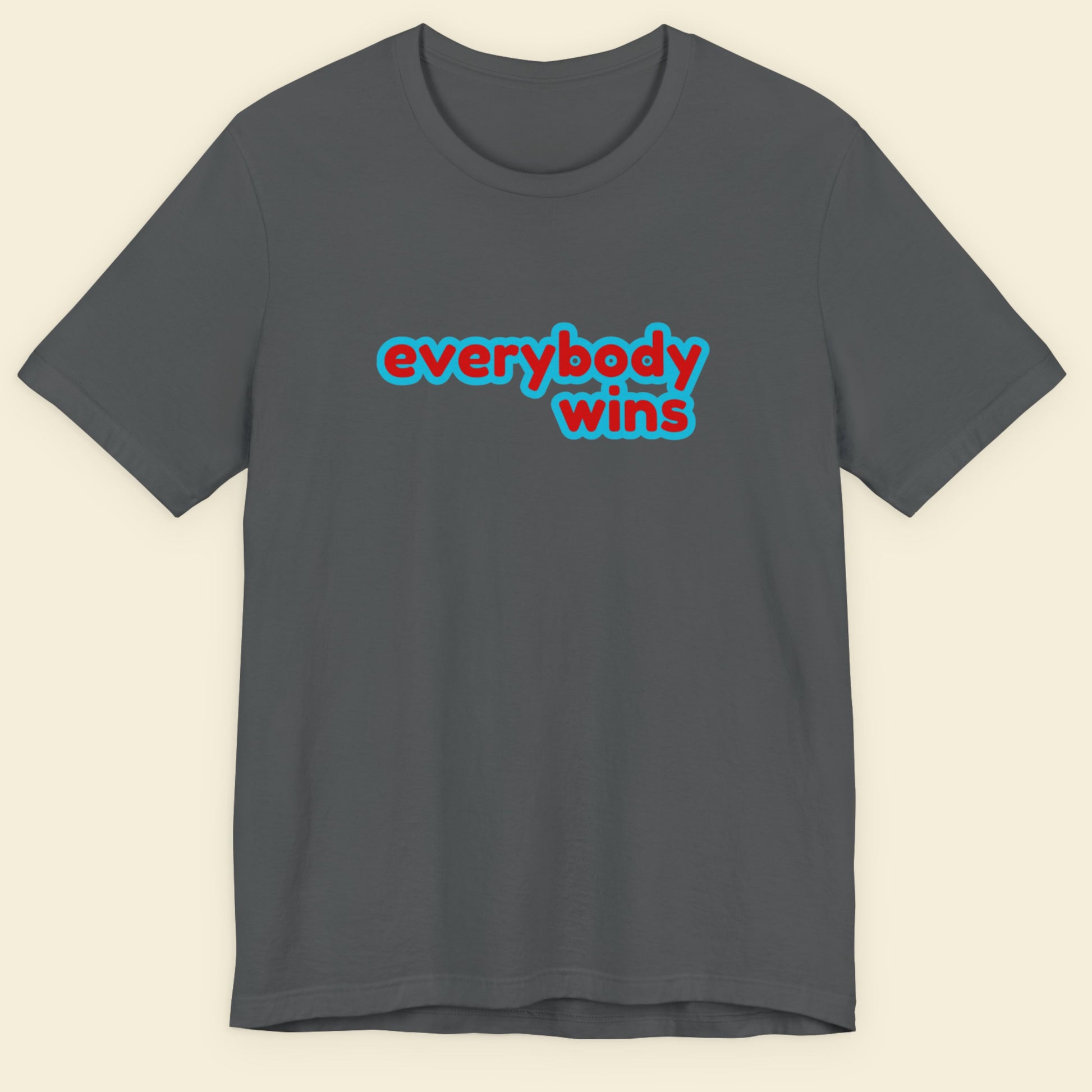 Grey t-shirt with multicolored everybody wins' text on a beige background.
