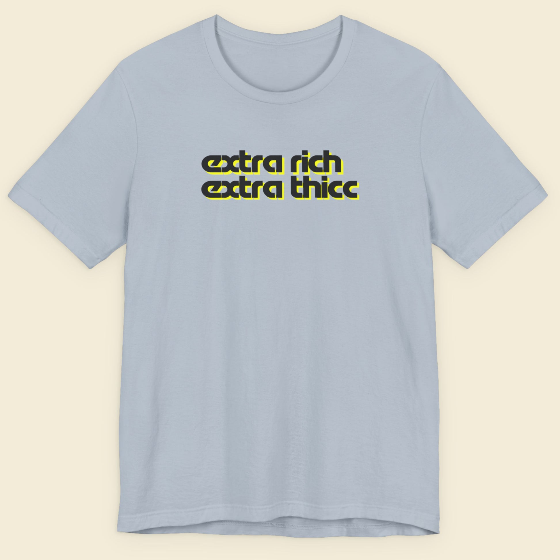 Light blue t-shirt with yellow text 'extra rich extra thicc' on a beige background.