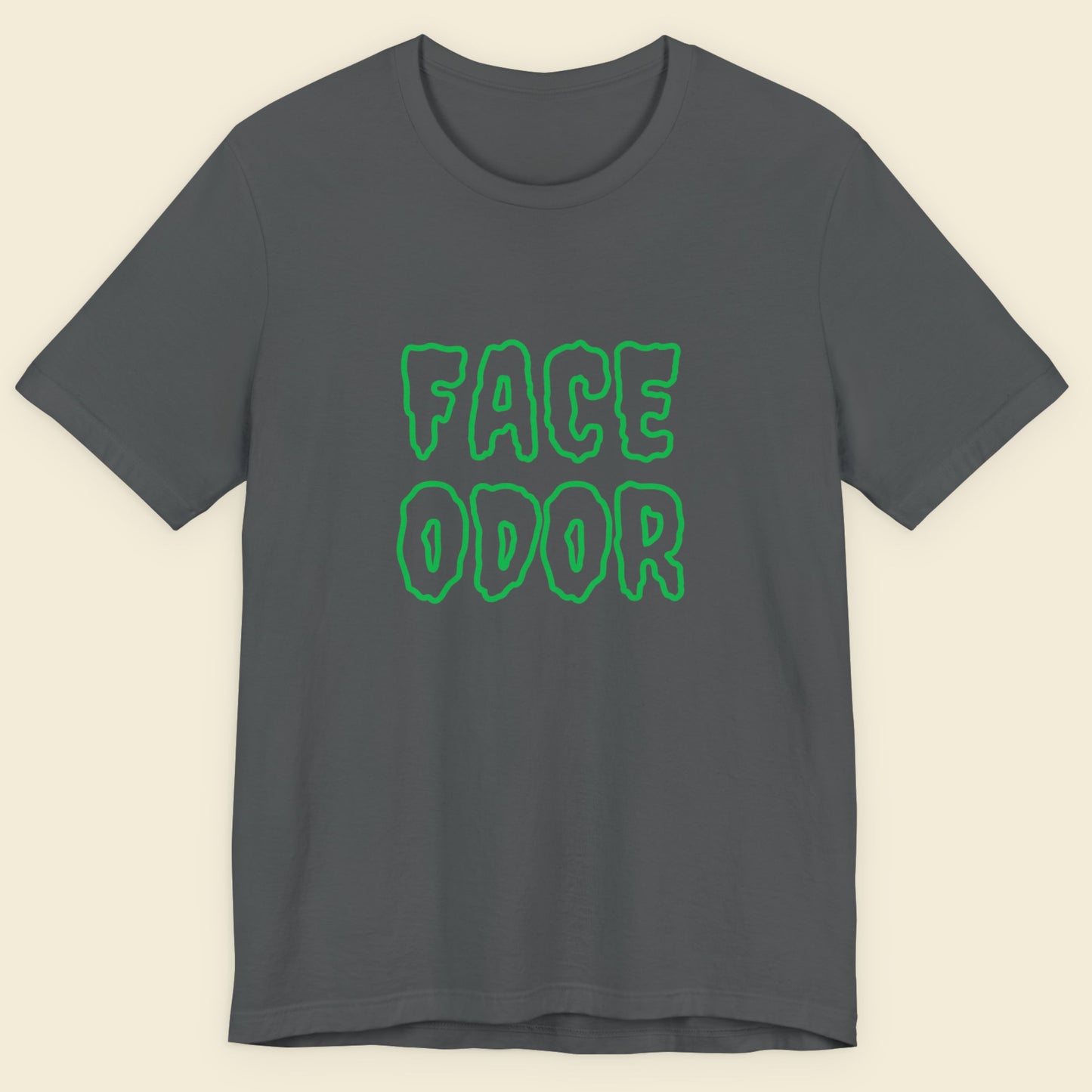 Gray t-shirt with green 'FACE ODOR' text on a beige background.