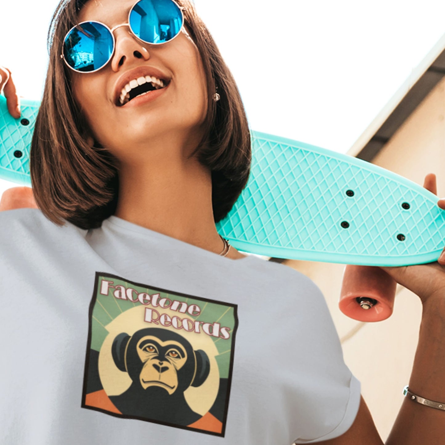 Person holding a turquoise skateboard with a graphic t-shirt featuring a monkey design.