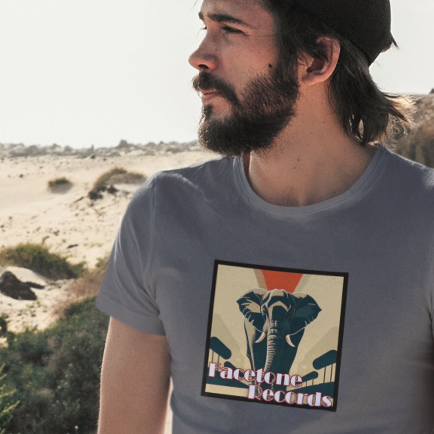 Man wearing a t-shirt with an elephant graphic and 'Facetone Records' text in a desert setting