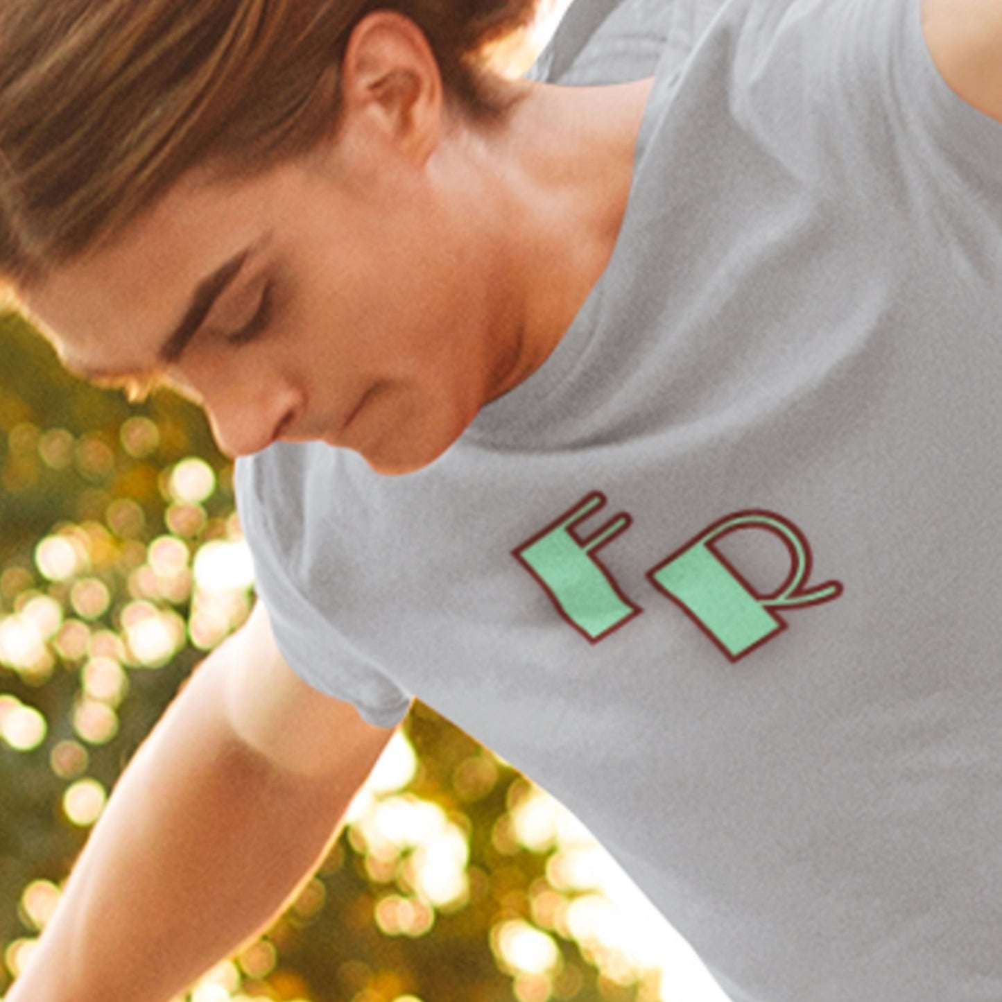 Person wearing a light gray t-shirt with 'FR' logo outdoors