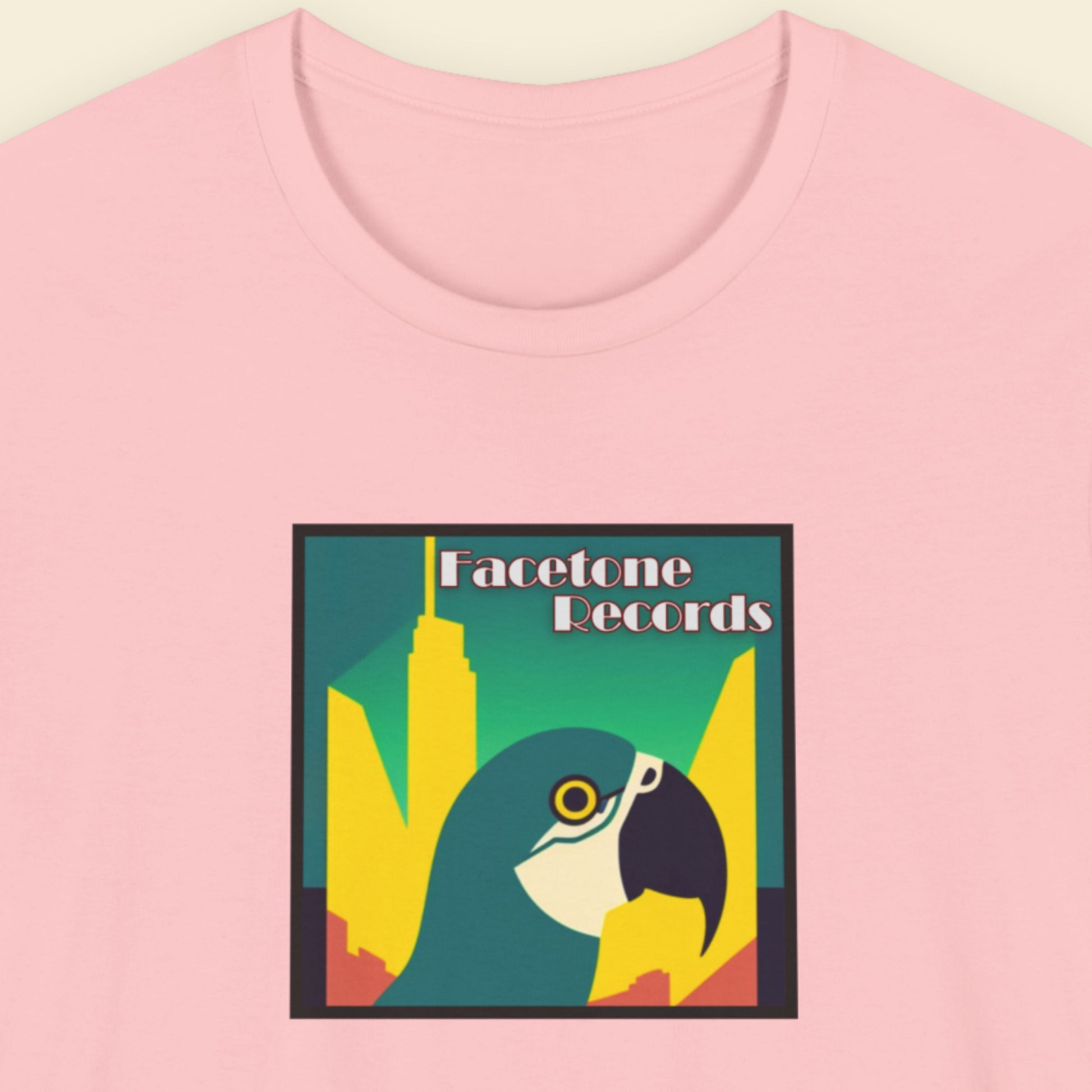 Pink t-shirt with a graphic design featuring a macaw and 'Facetone Records' text on a beige background