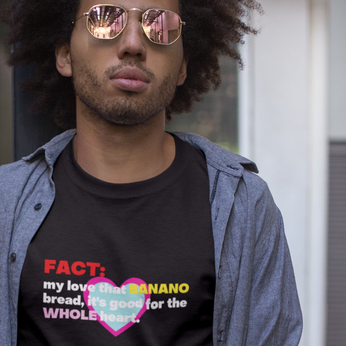 Person wearing a black t-shirt with colorful text and graphics, standing outdoors.