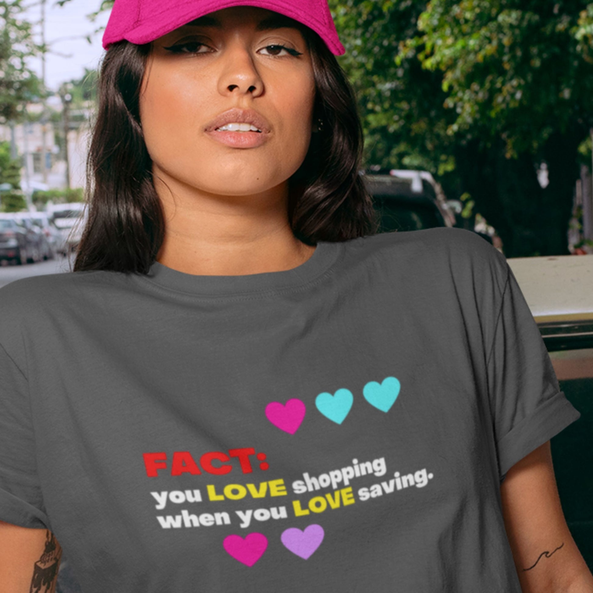 Woman wearing a grey t-shirt with humorous colorful text outside.