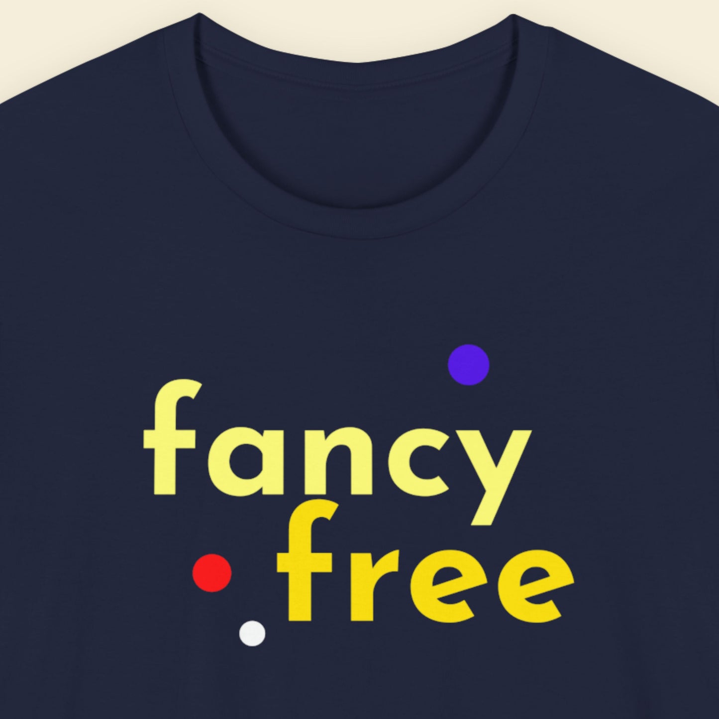Navy blue t-shirt with 'fancy free' text in yellow and colorful dots on a beige background.
