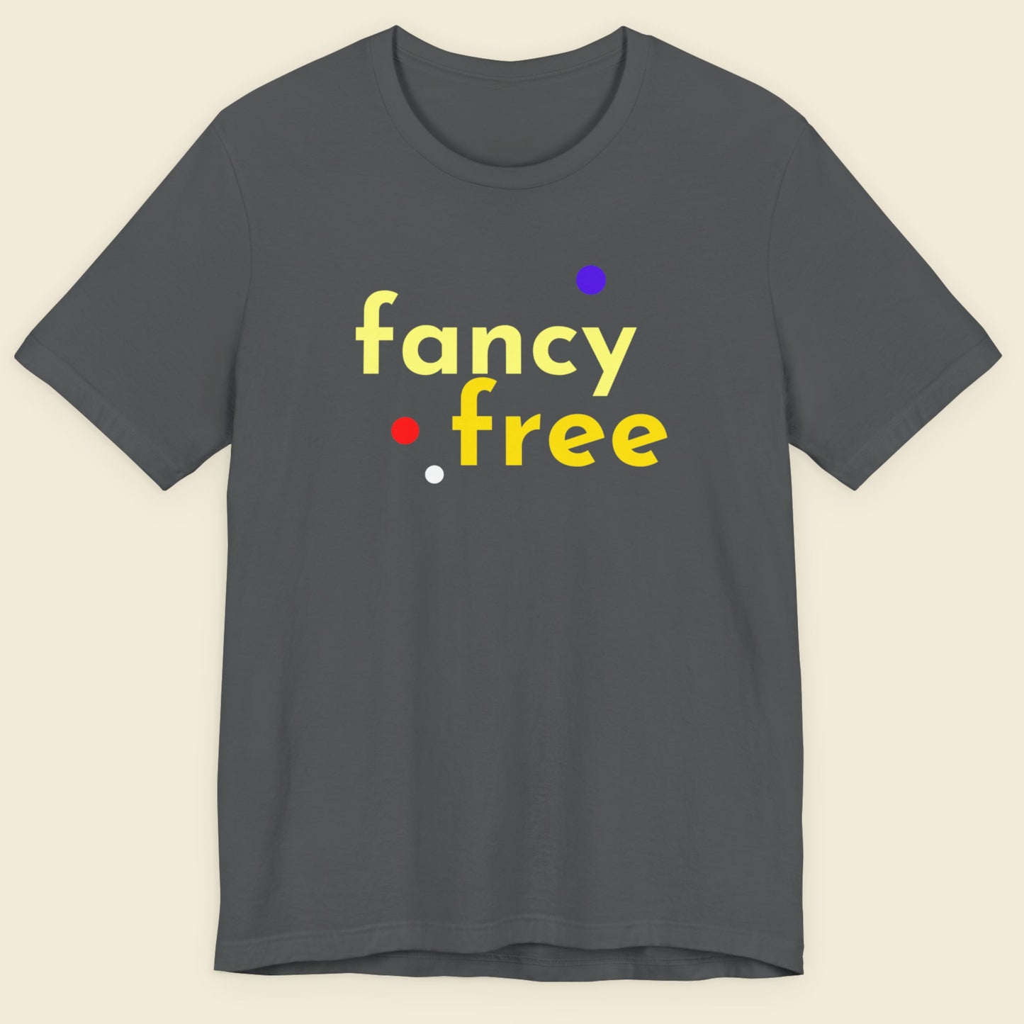 Gray t-shirt with 'fancy free' text in yellow and colorful dots on a beige background.