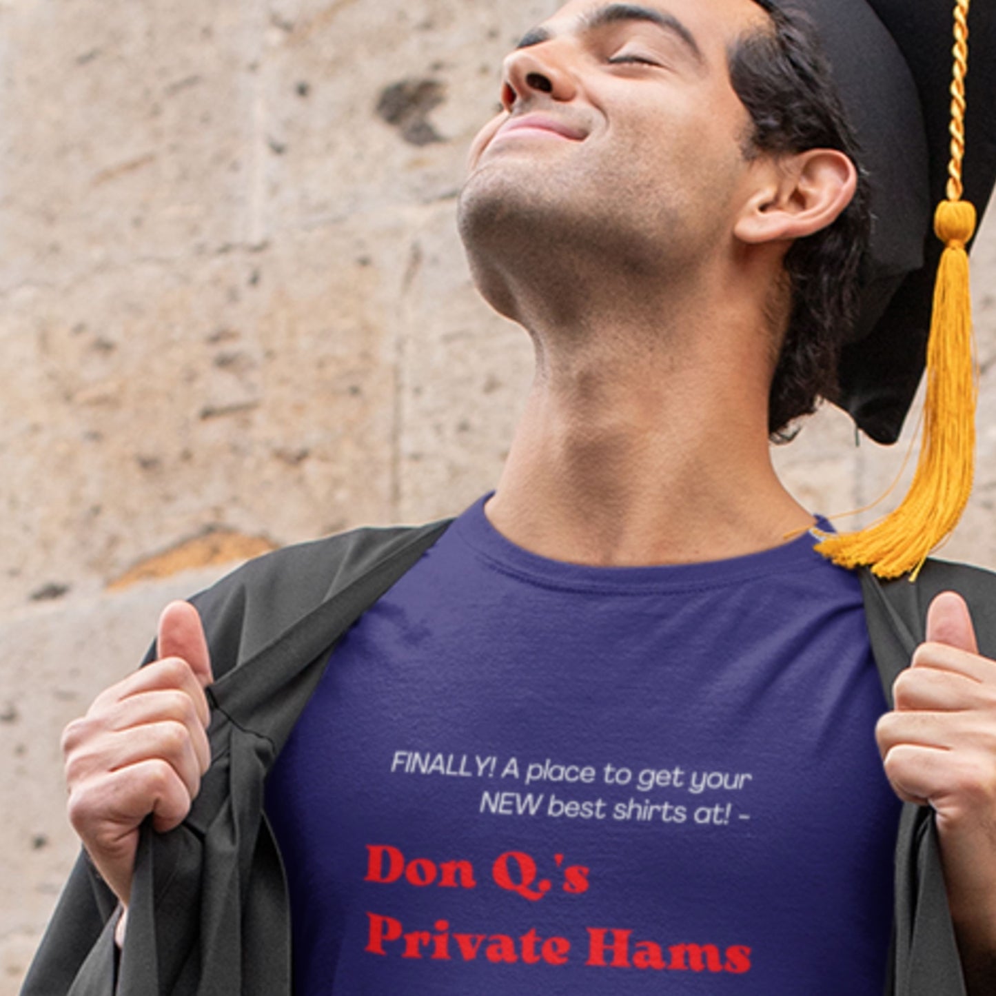 Graduate wearing a blue t-shirt with humorous text, standing against a stone wall.
