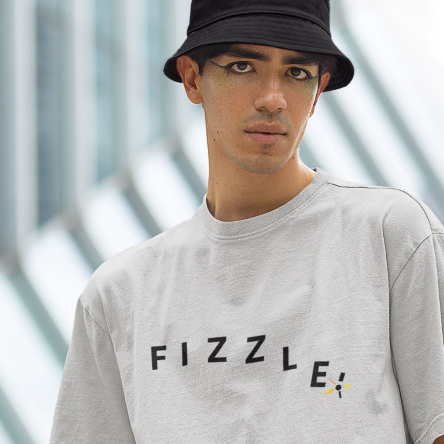 Light grey shirt with fizzle written in a descending manner worn by a hat wearing model