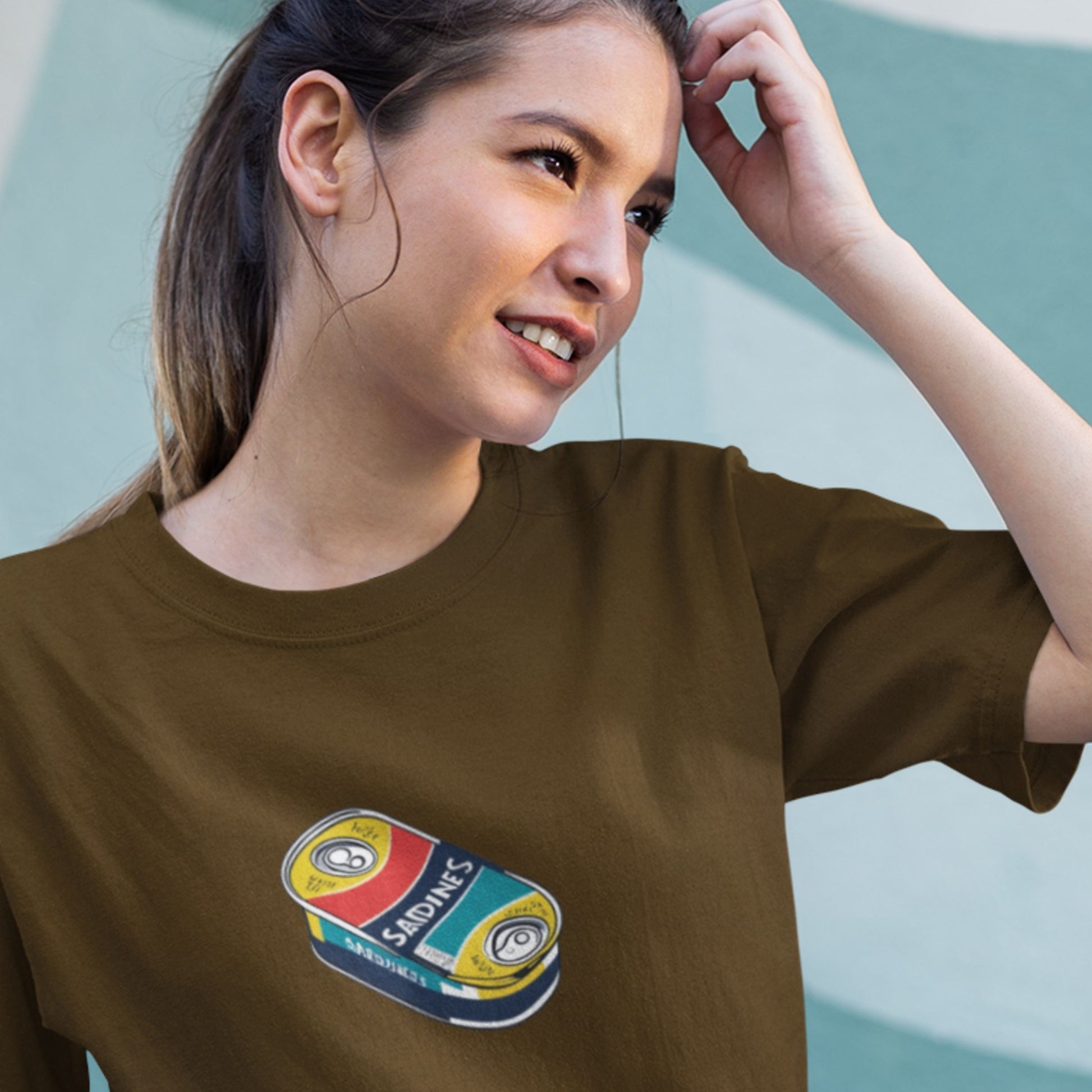 Woman wearing a brown shirt with an illustration of a flat can of sardines