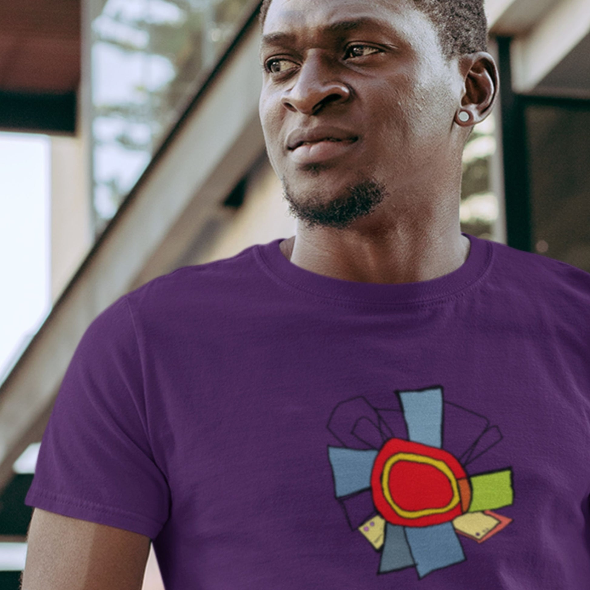 Man wearing a purple t-shirt with a colorful abstract diagram drawing in a gym.