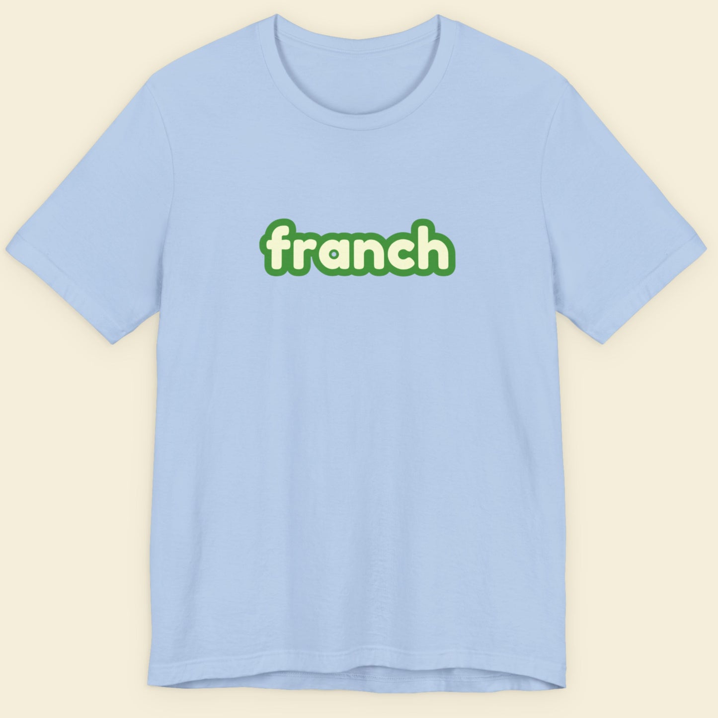 Baby blue t-shirt with humorous colorful franch text on a beige background.