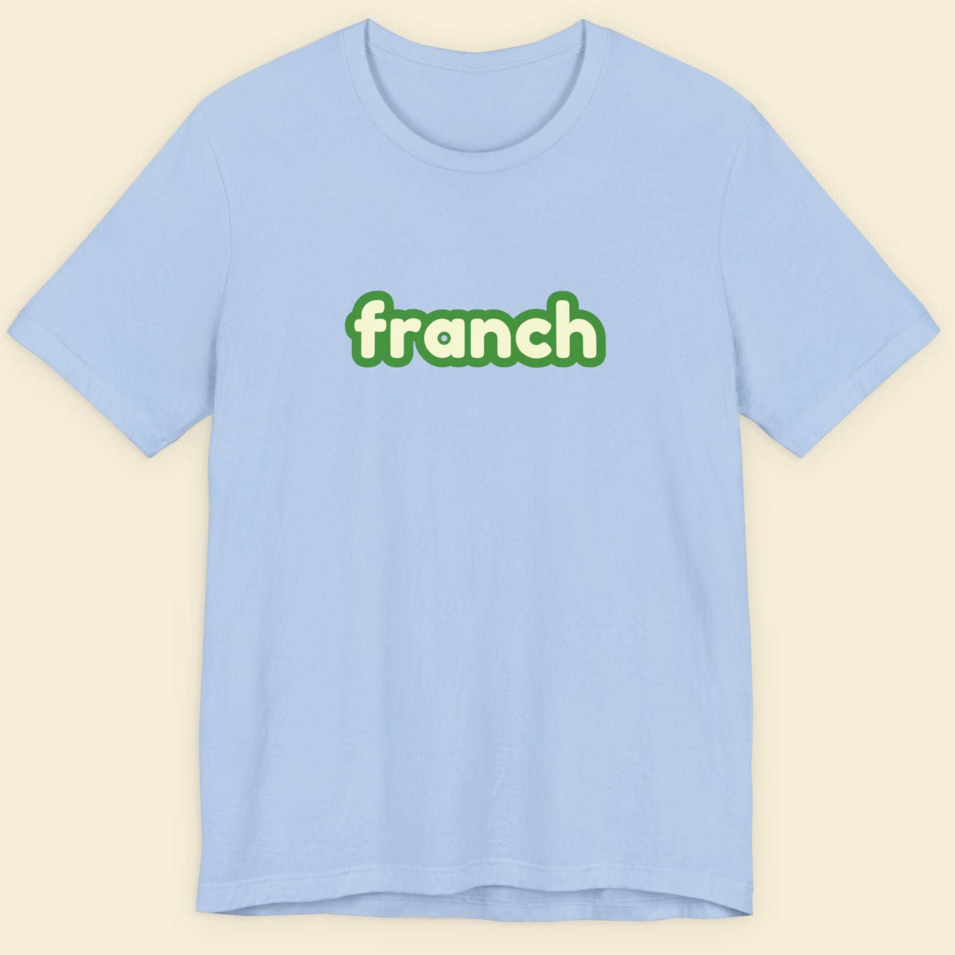 Baby blue t-shirt with humorous colorful franch text on a beige background.