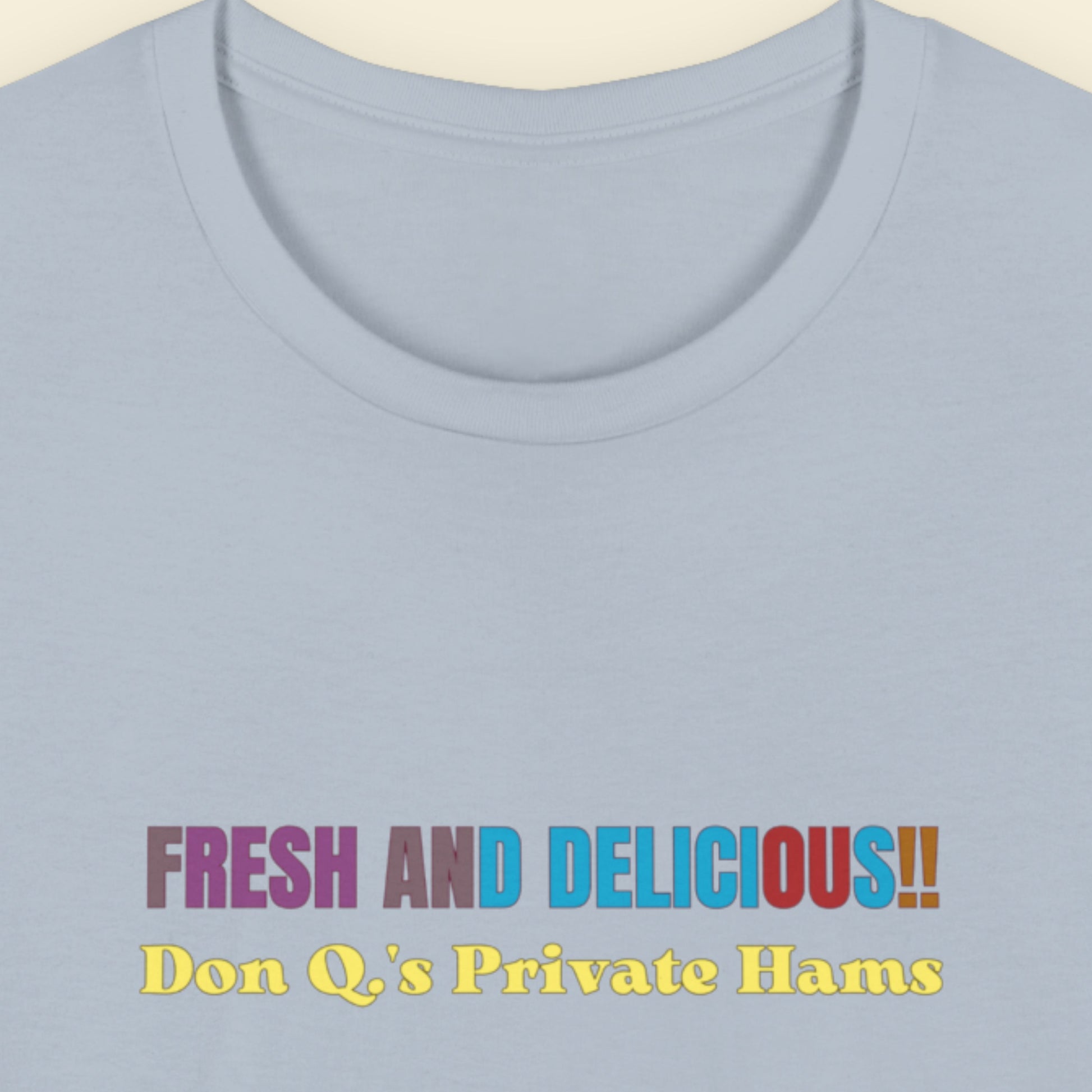 Light blue t-shirt with humorous colorful text on a beige background.