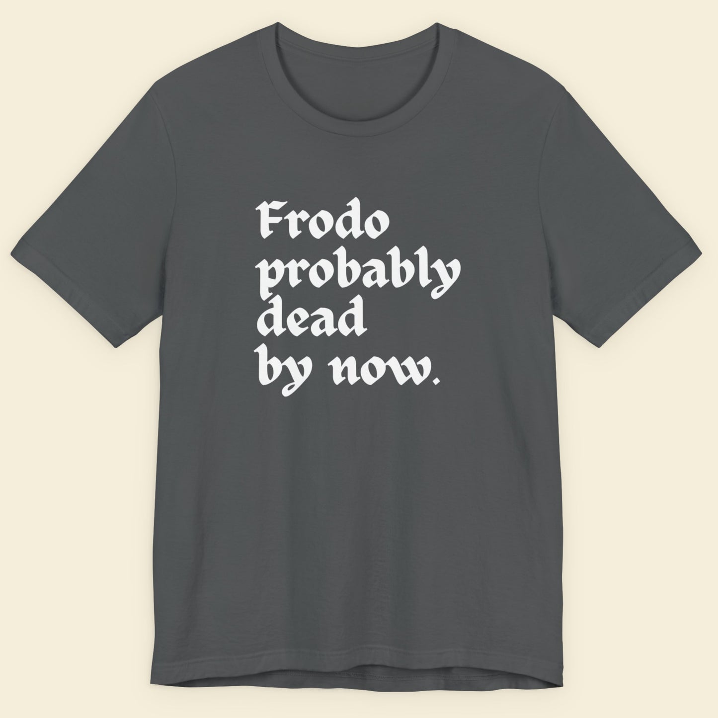 Gray t-shirt with white text 'Frodo probably dead by now' on a beige background.