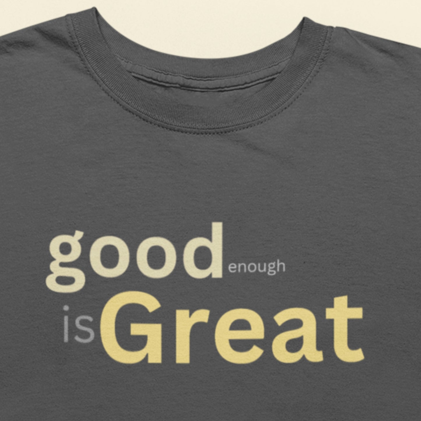 Gray t-shirt with 'good enough is Great' text in yellow on a beige background