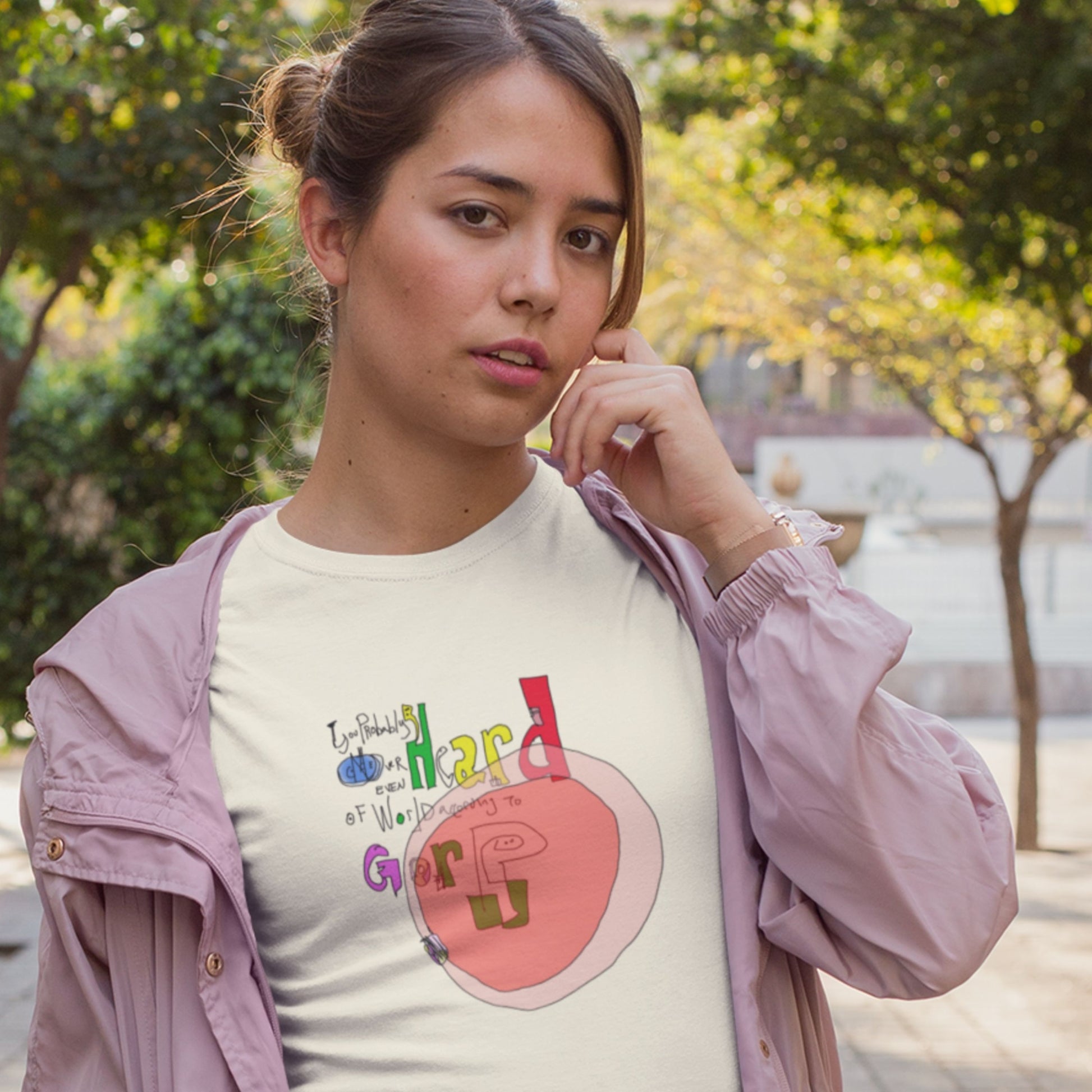 Woman wearing a cream colored t-shirt with a colorful abstract graffiti drawing outside.