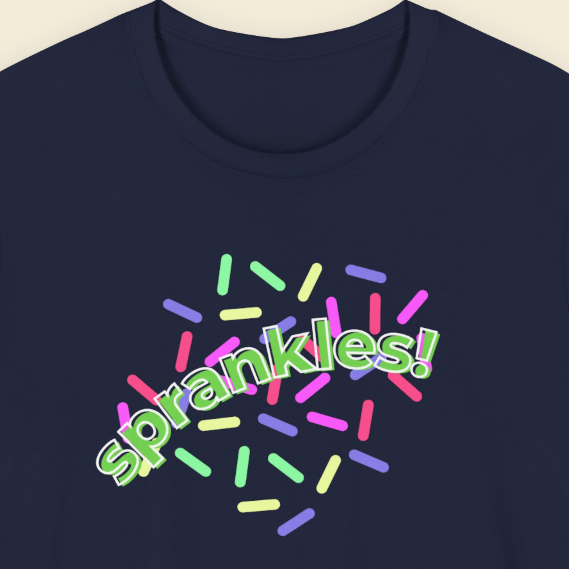 Navy blue t-shirt with humorous colorful text on a beige background.