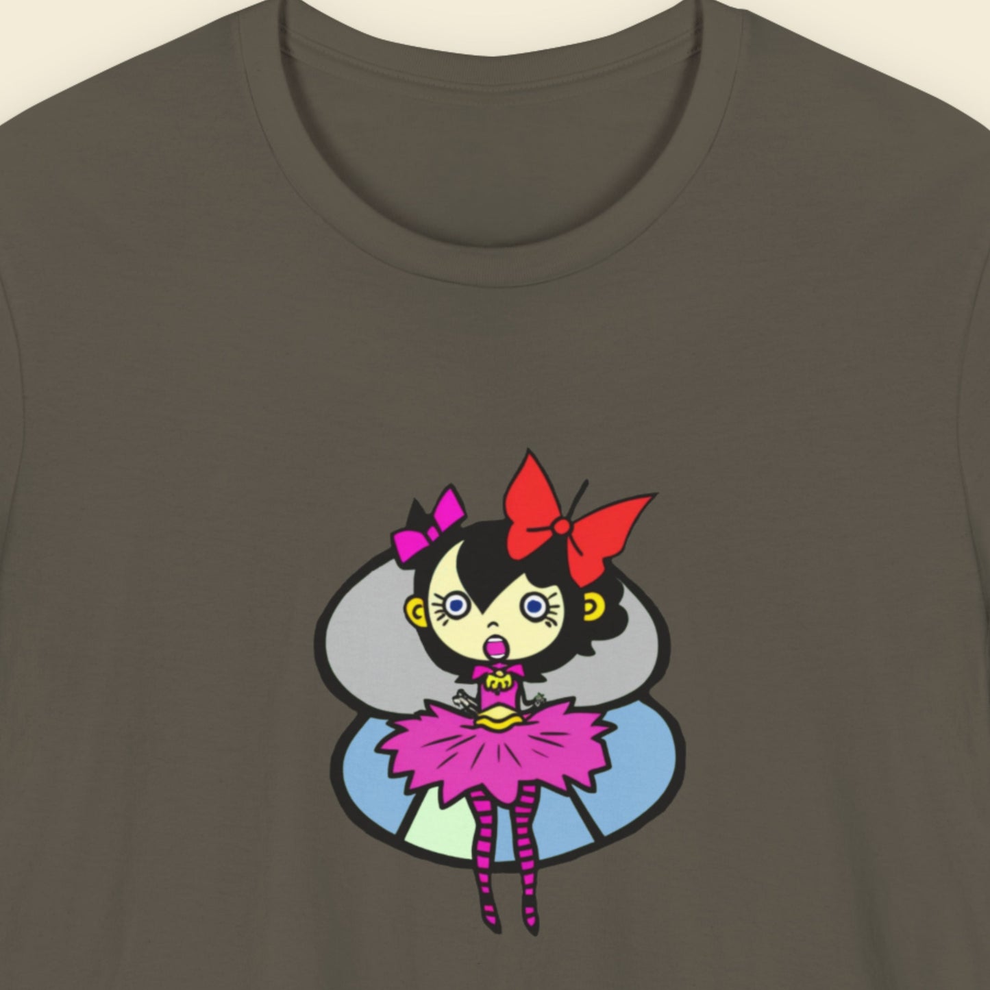 Army green t-shirt with a fun, colorful cartoon pixie illustration on a beige background.