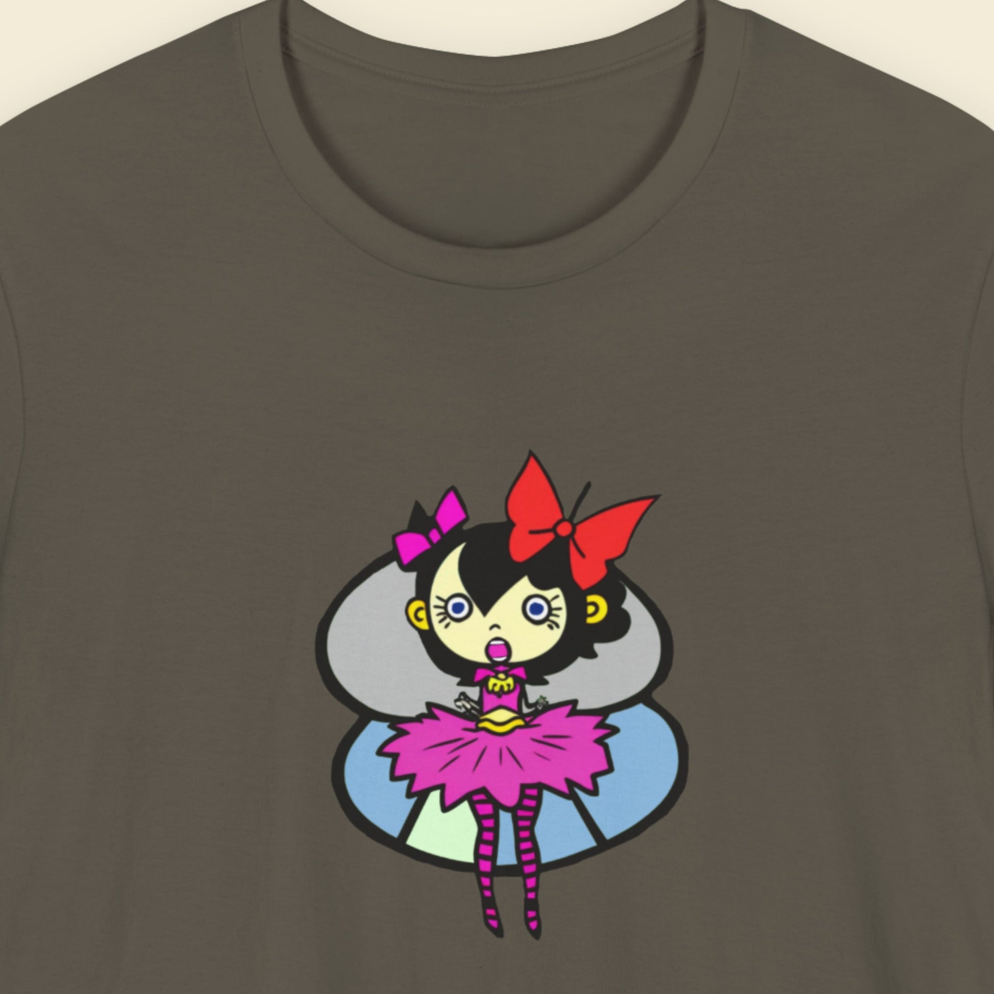 Army green t-shirt with a fun, colorful cartoon pixie illustration on a beige background.