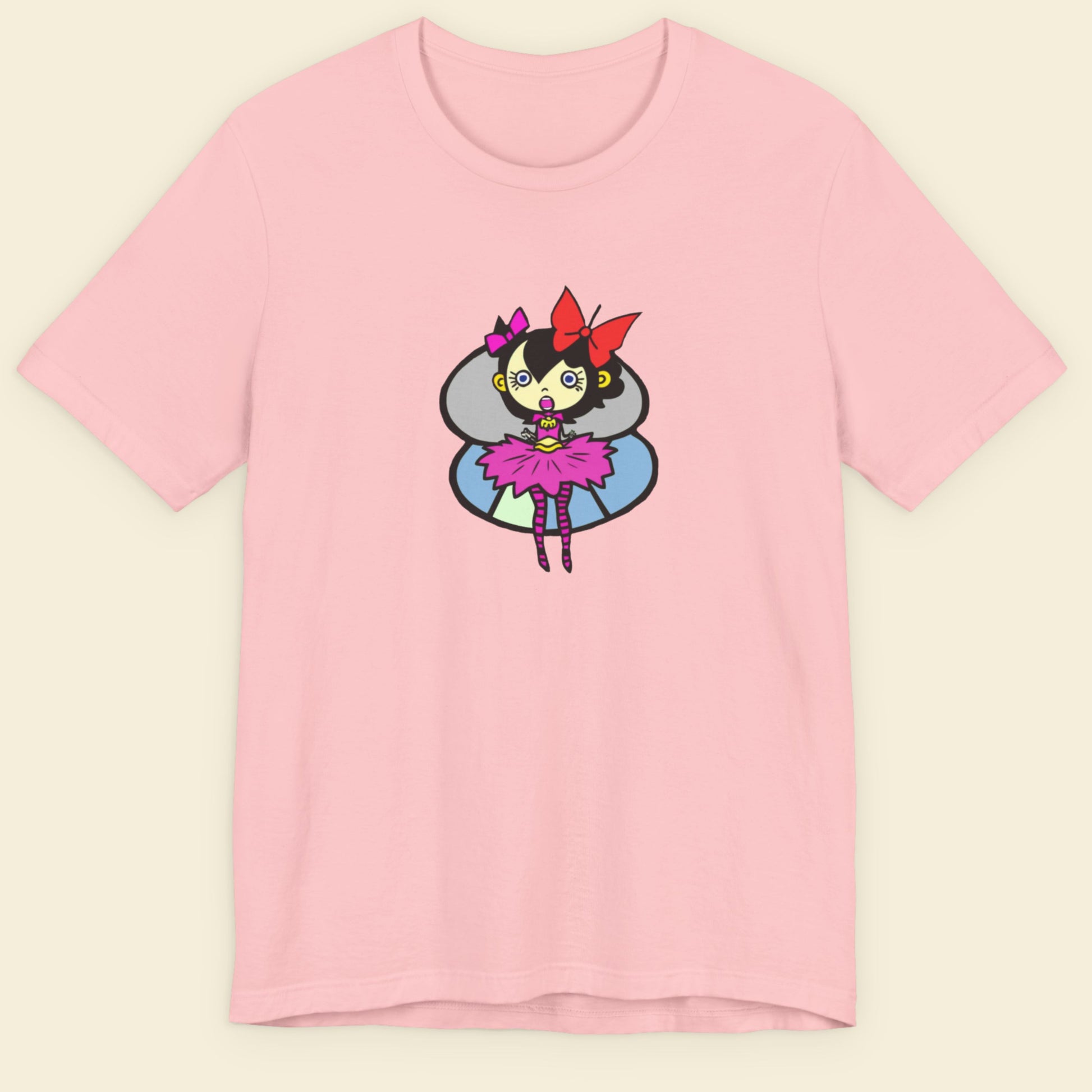 Pink t-shirt with a fun, colorful cartoon pixie illustration on a beige background.