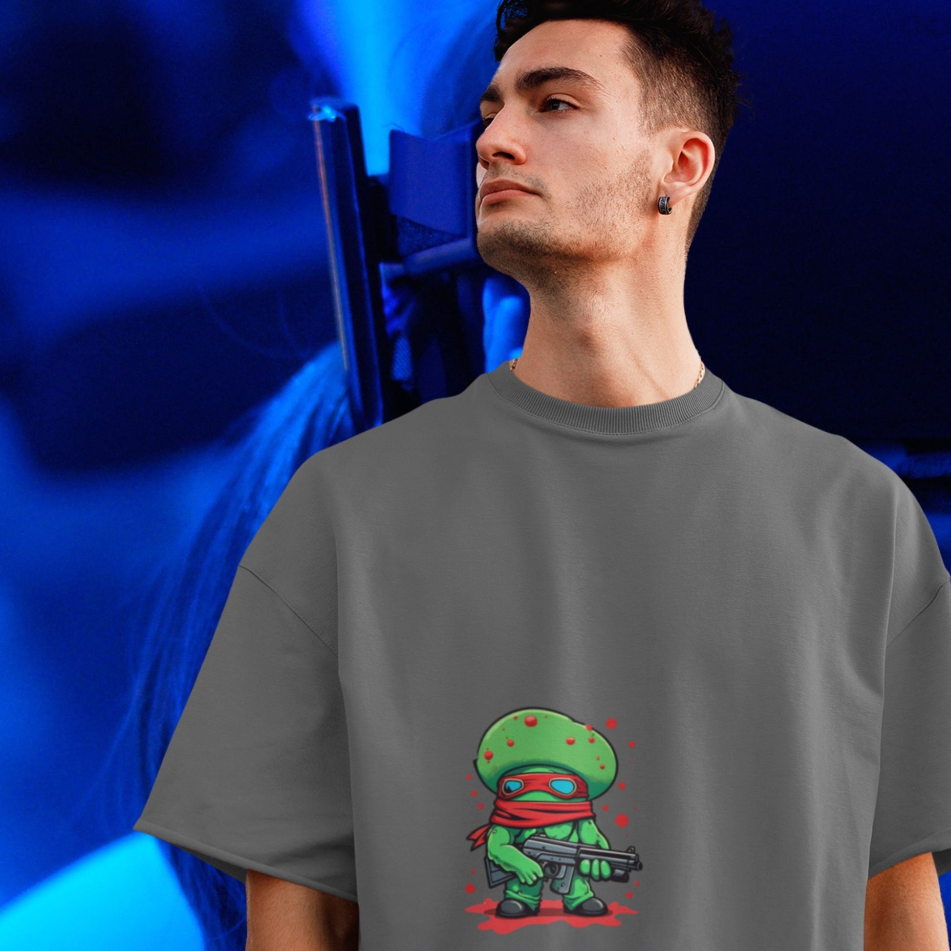 Person wearing a gray t-shirt with a green character design on a blue background
