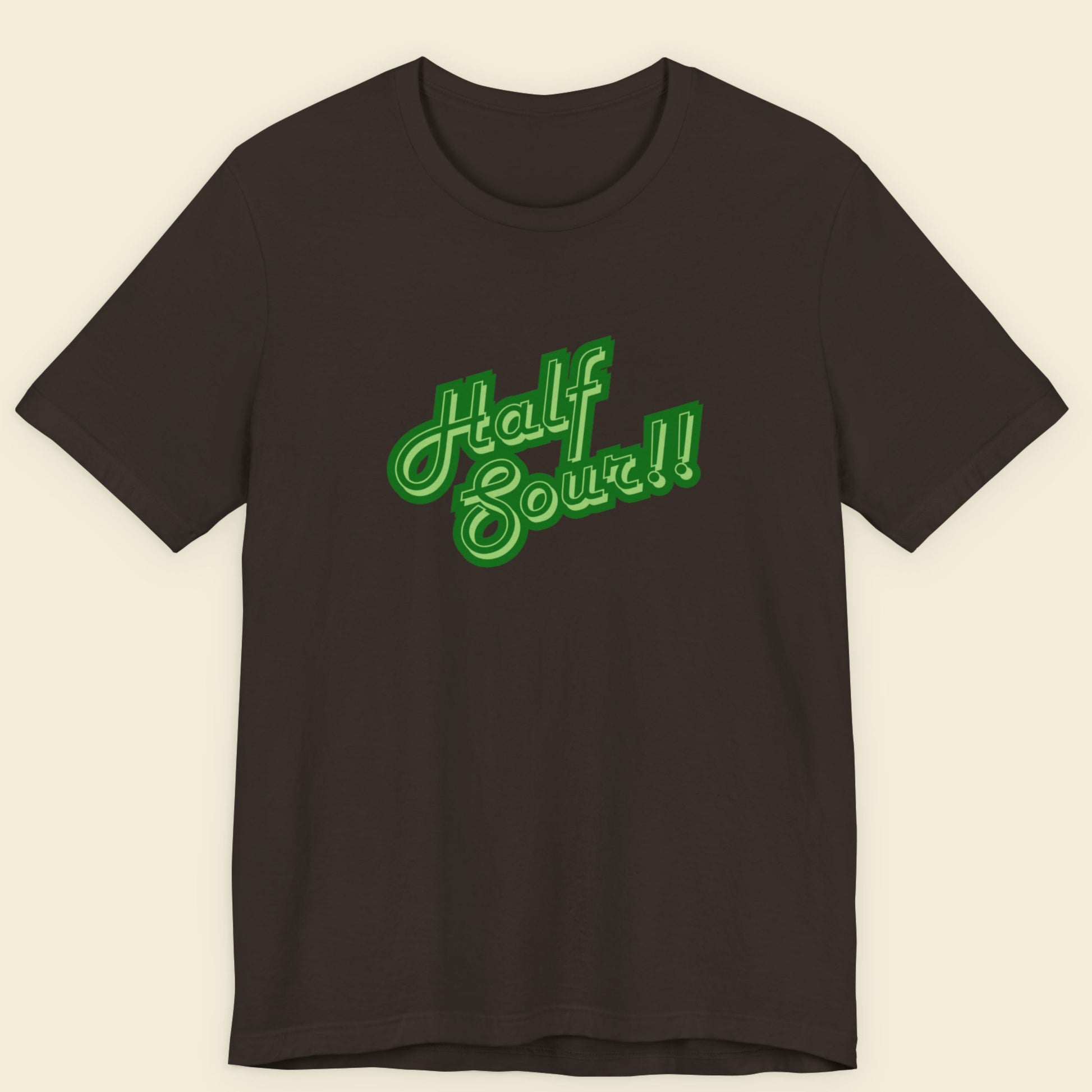 Brown shirt with green 'half sour!!' text on a beige background.