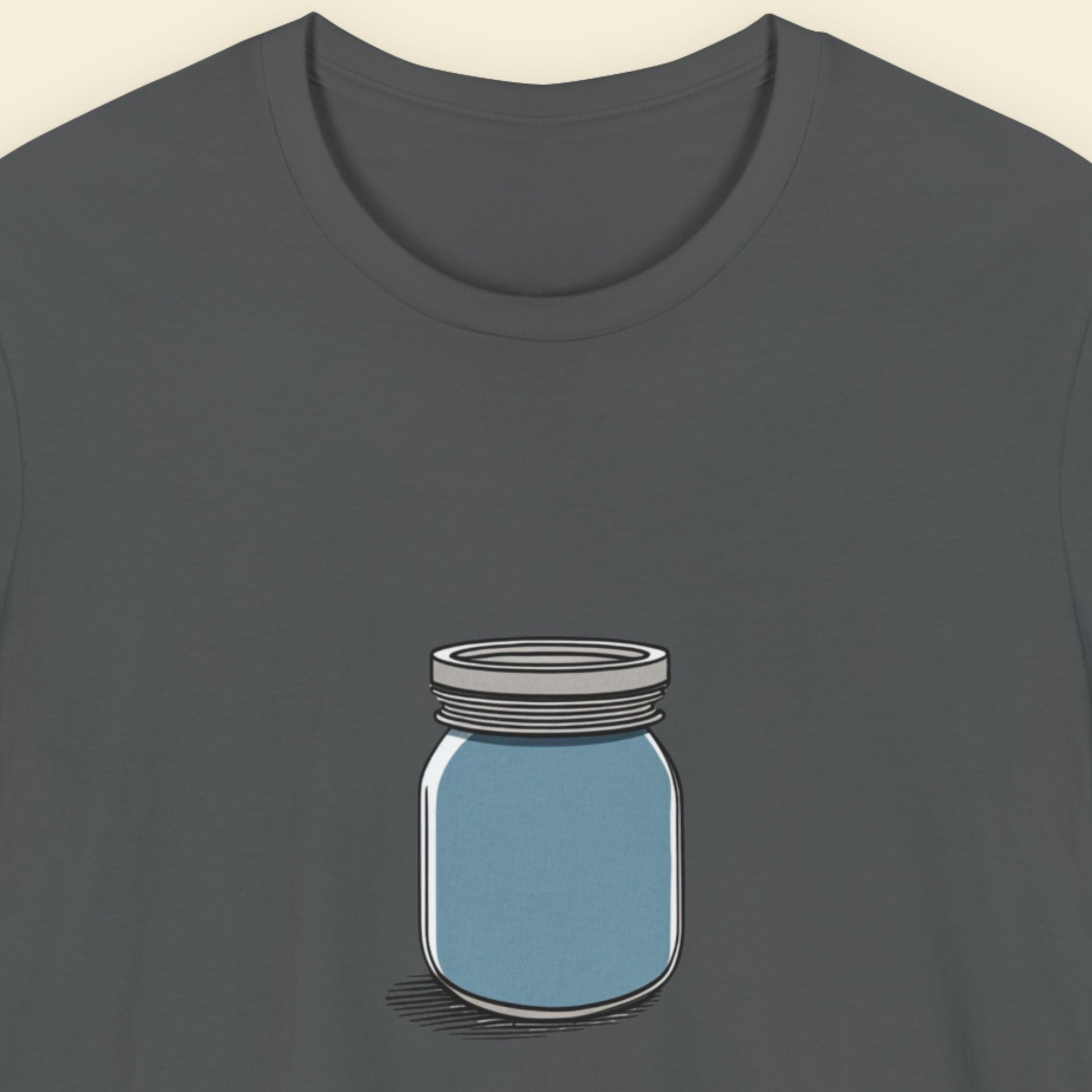 Grey shirt with a drawing of a blue jar against a beige background.