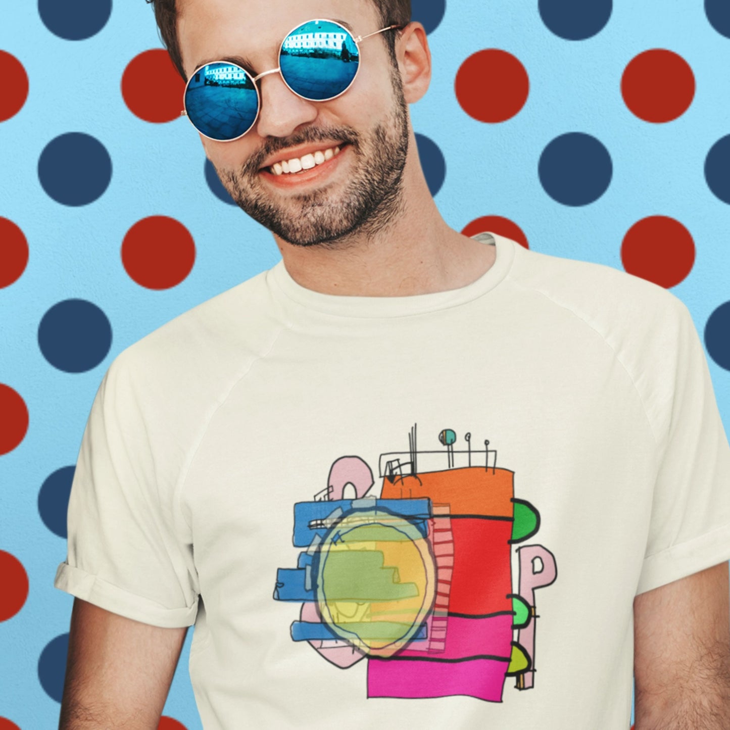 Man wearing a cream colored t-shirt with a colorful abstract drawing on a polka-dot background.