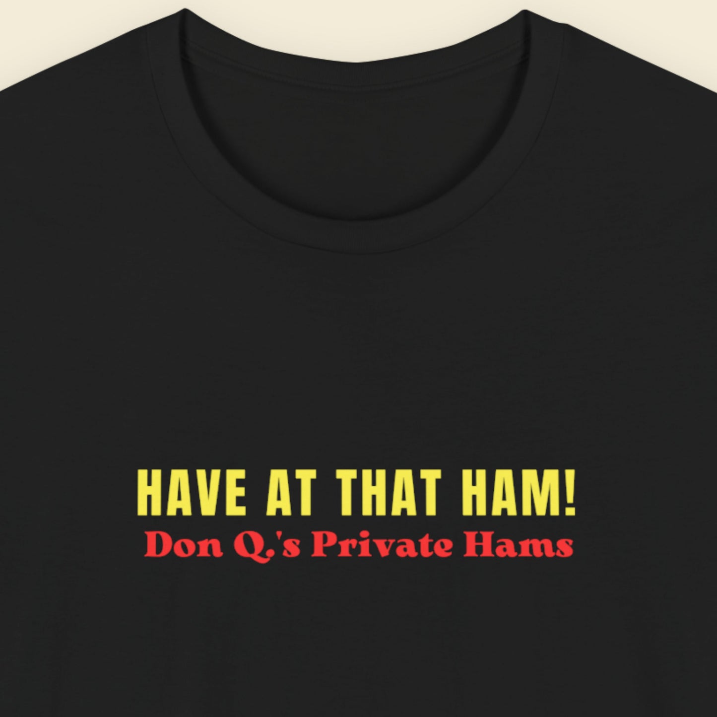 black shirt with colorful have at that ham! text on a beige background.
