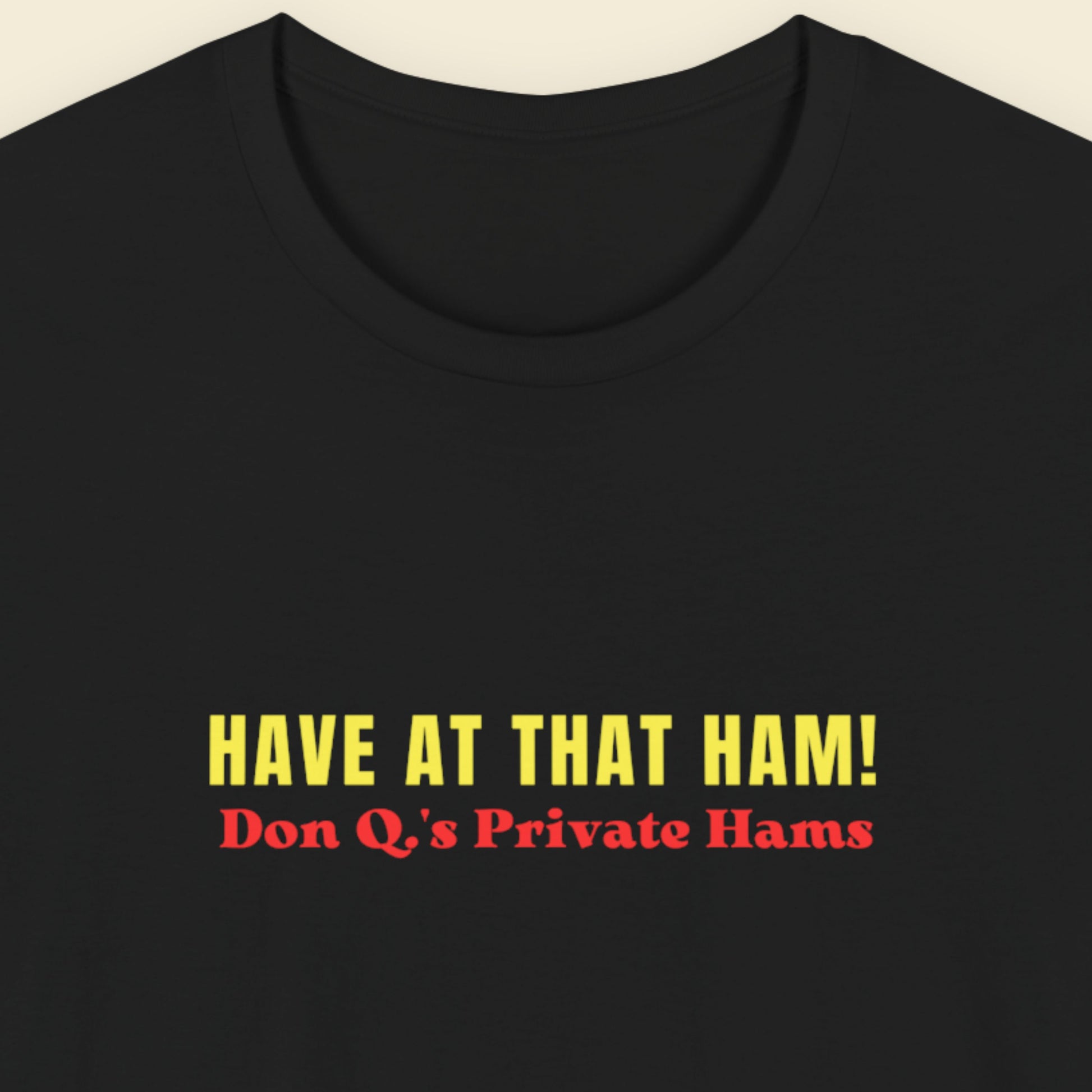 black shirt with colorful have at that ham! text on a beige background.